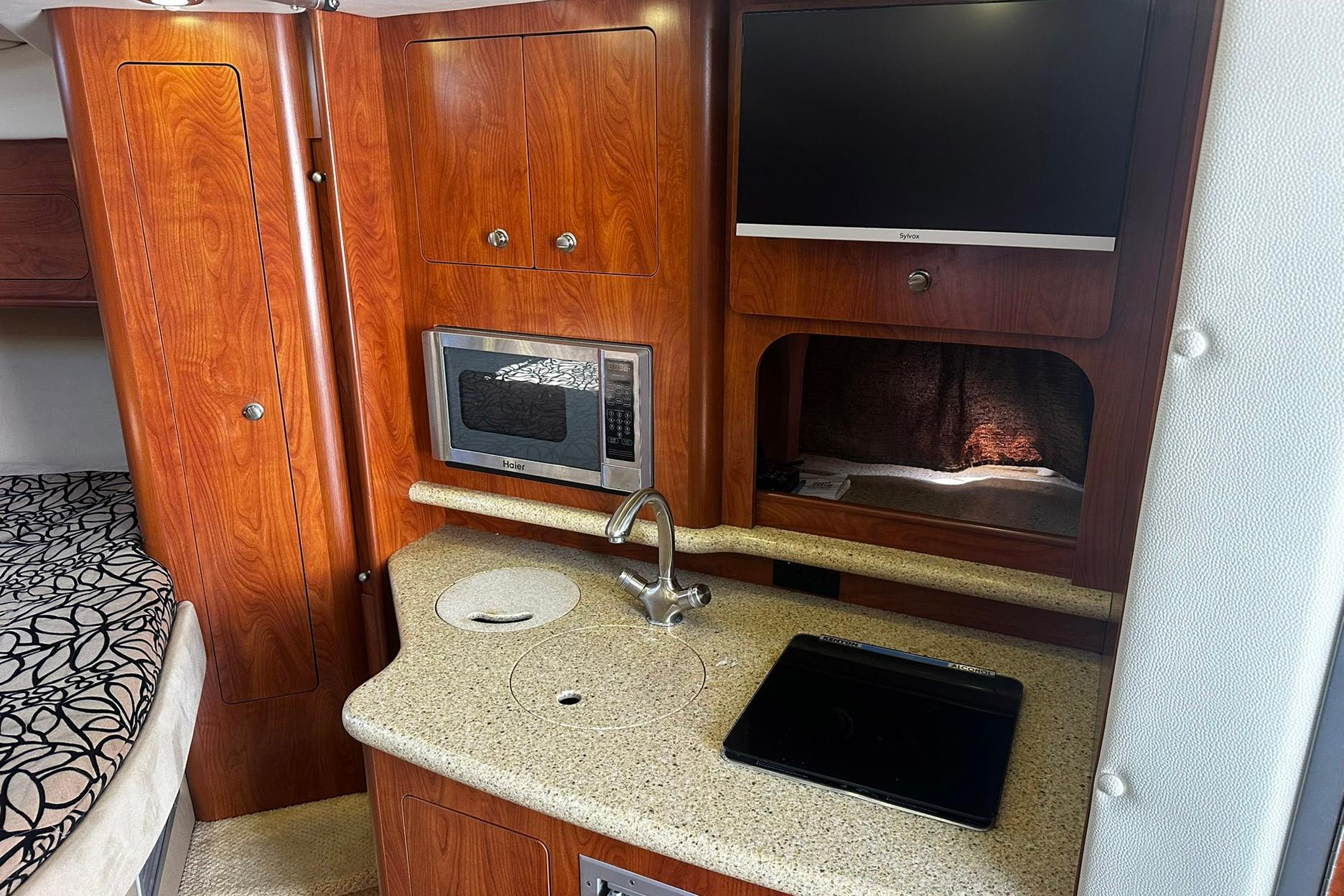 2012 Rinker 310 Express Cruiser LE interior with kitchenette, microwave, and TV.