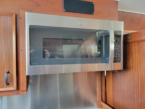 A modern microwave is installed in a wooden kitchen.