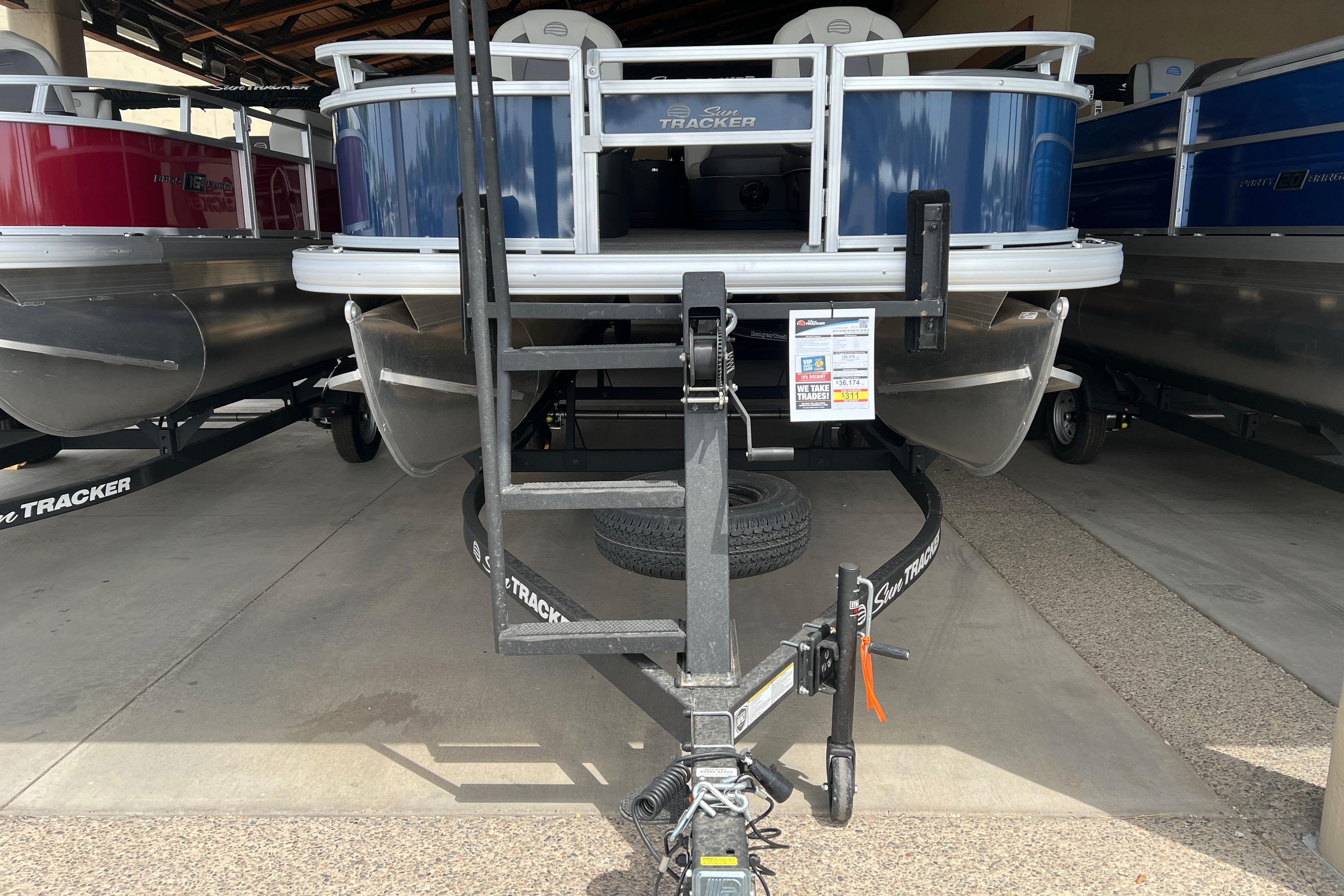 2026 Sun Tracker Bass Buggy 18 DLX pontoon boat on trailer in showroom.