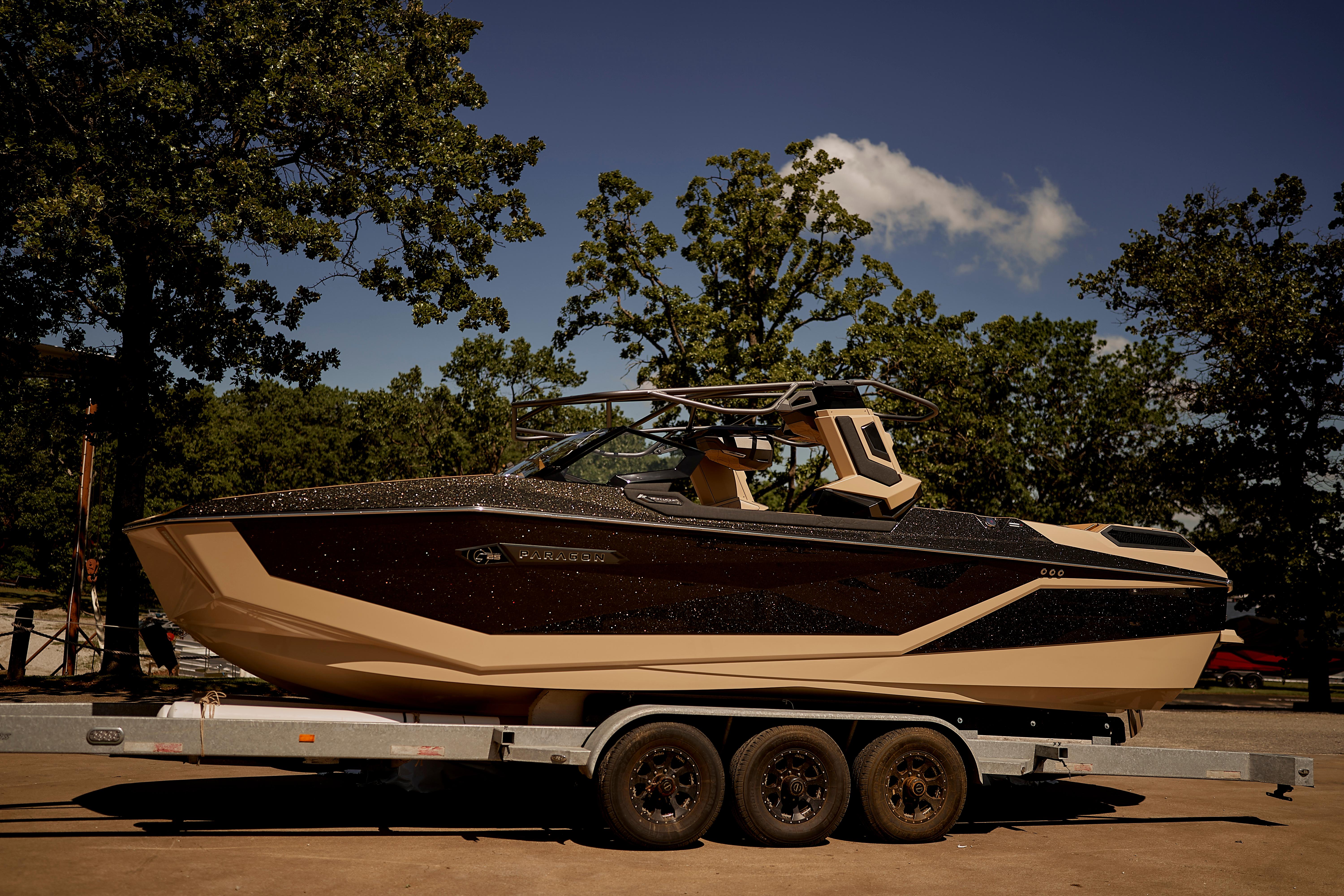 2025 Nautique Super Air Nautique G25 Paragon boat on trailer, surrounded by trees.