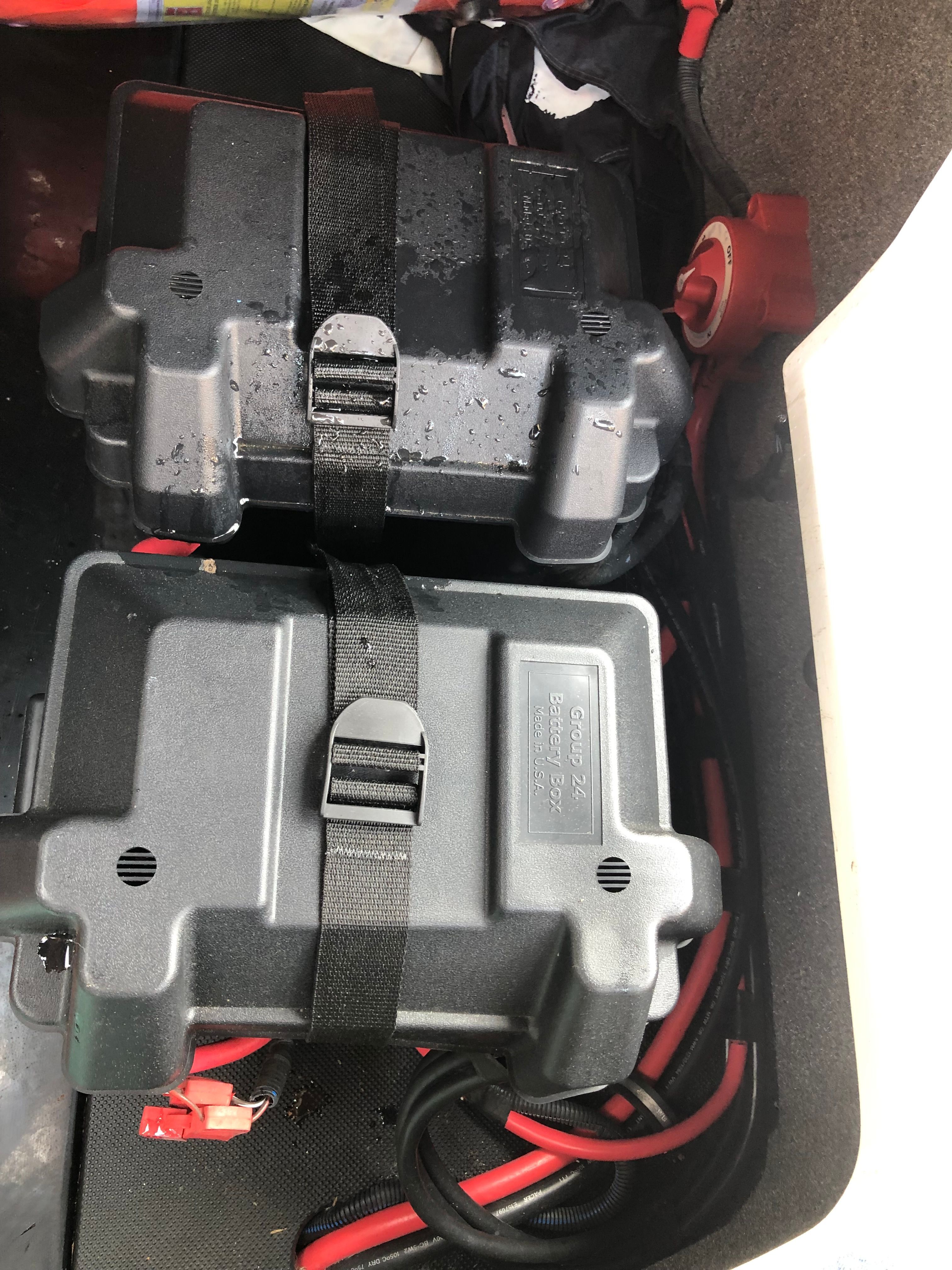 Two black battery boxes with straps in a vehicle.