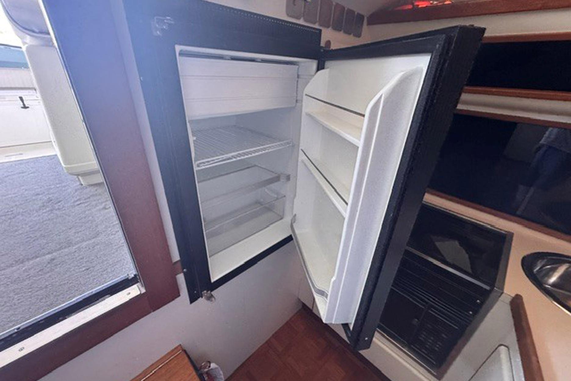 Open refrigerator inside 1988 Tiara Yachts 3300 Open, showcasing interior storage space.