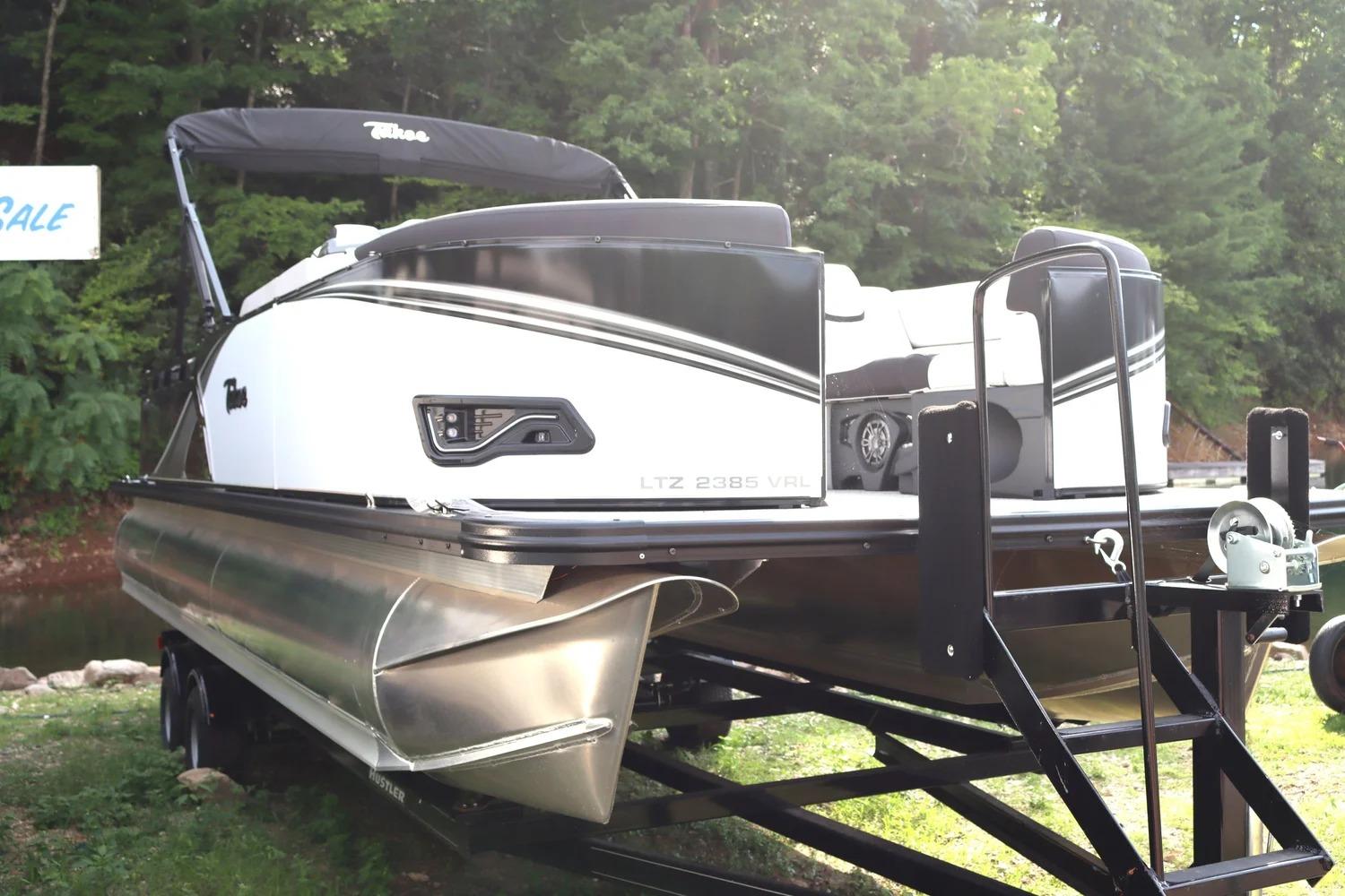 2024 Tahoe Pontoons LTZ2385 VRL on trailer, surrounded by lush greenery.