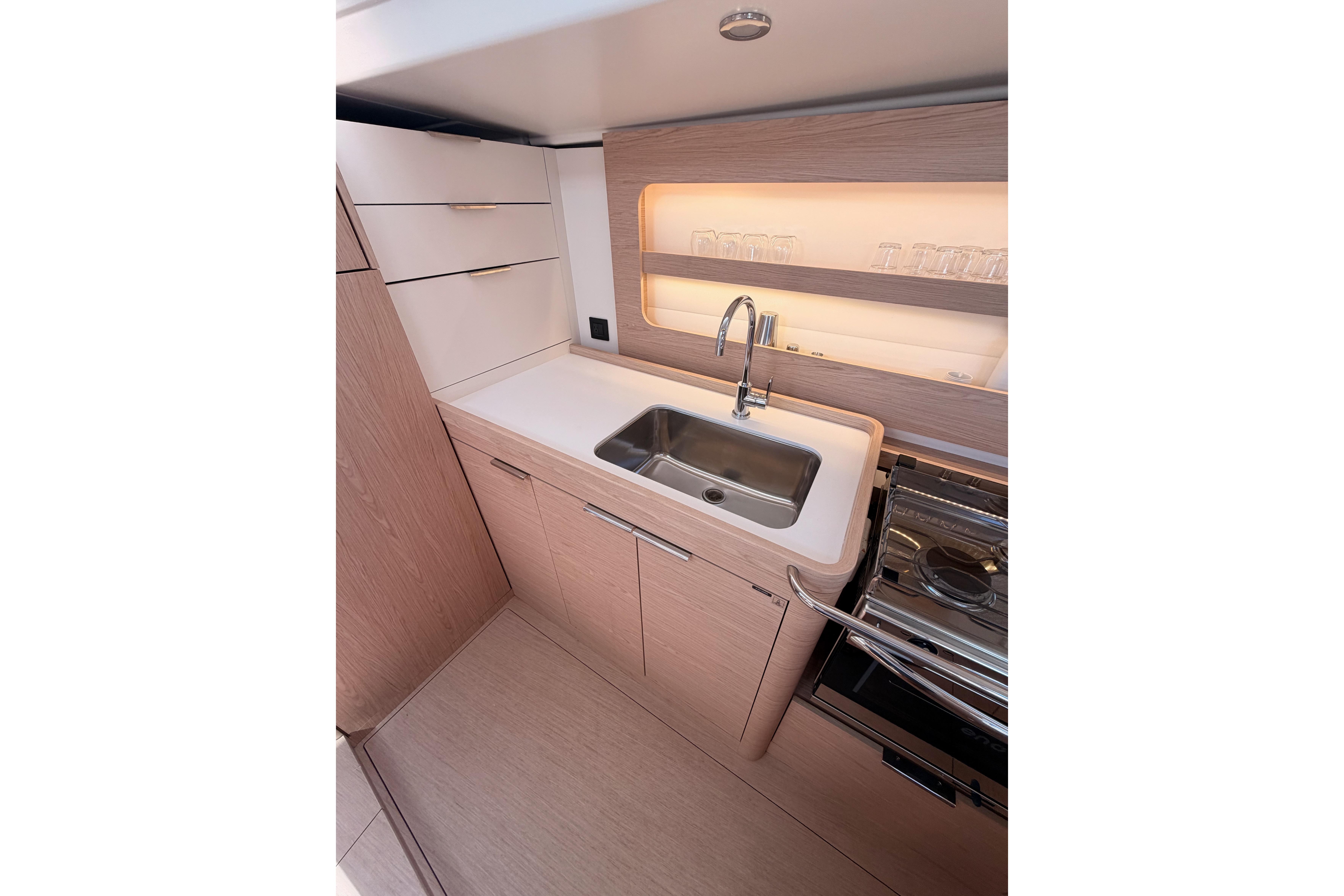Modern kitchen interior of 2022 Beneteau Oceanis Yacht 54, featuring sleek cabinetry and stainless steel sink.