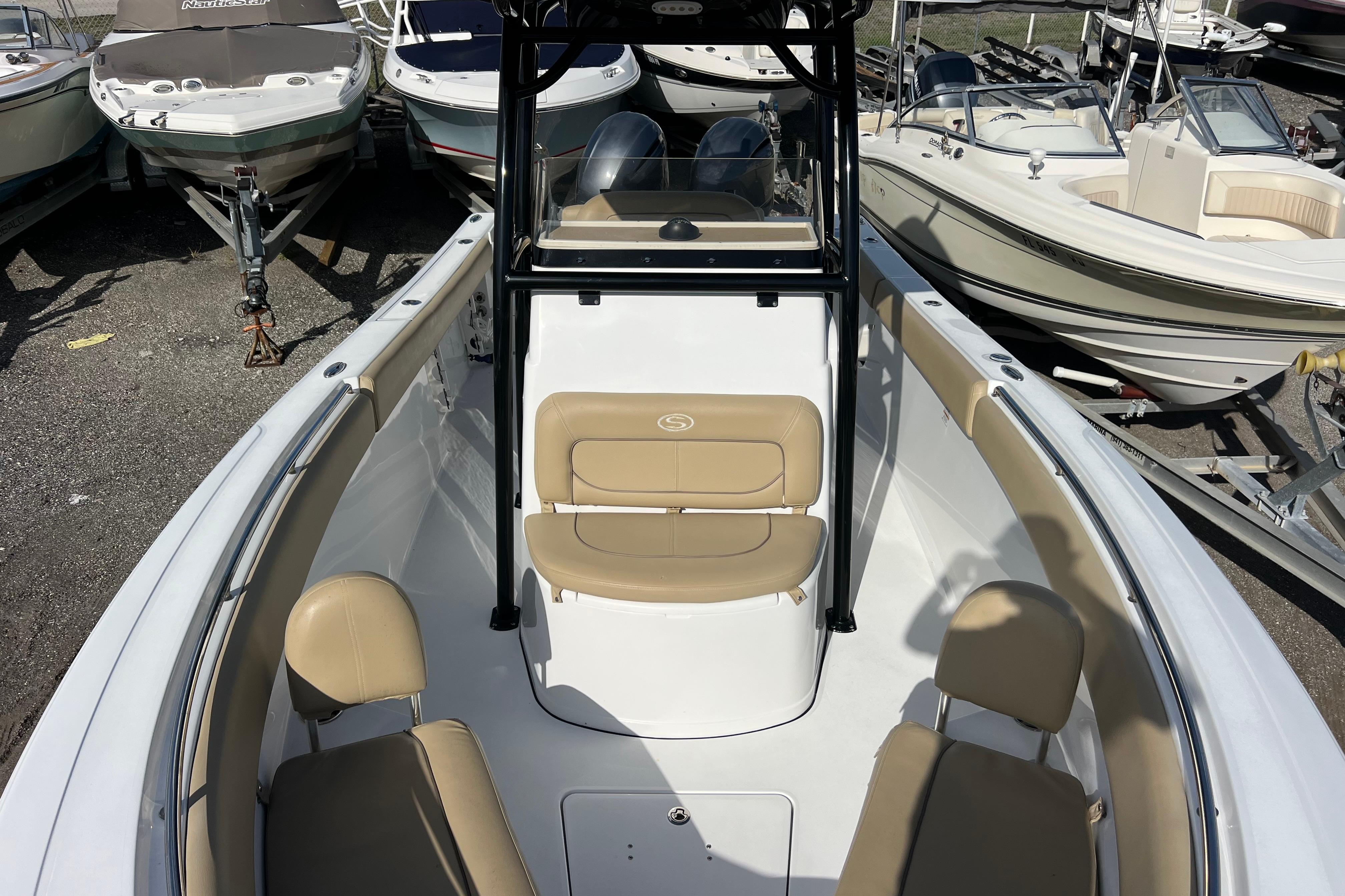 2017 Sportsman Heritage 251 Center Console boat with beige seating, docked among other boats.