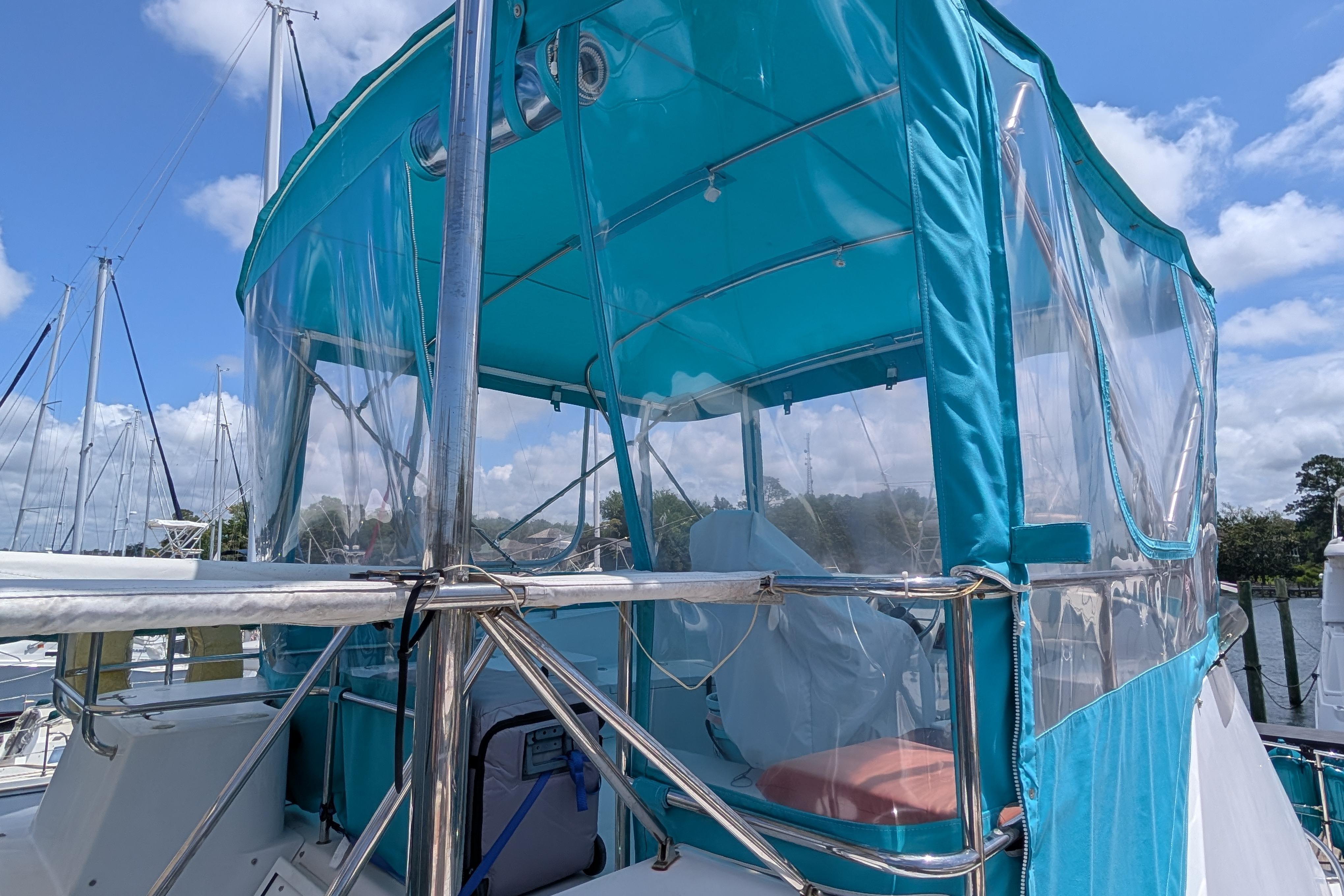 2004 PDQ 34 Powercat with blue canopy, docked under a clear sky.