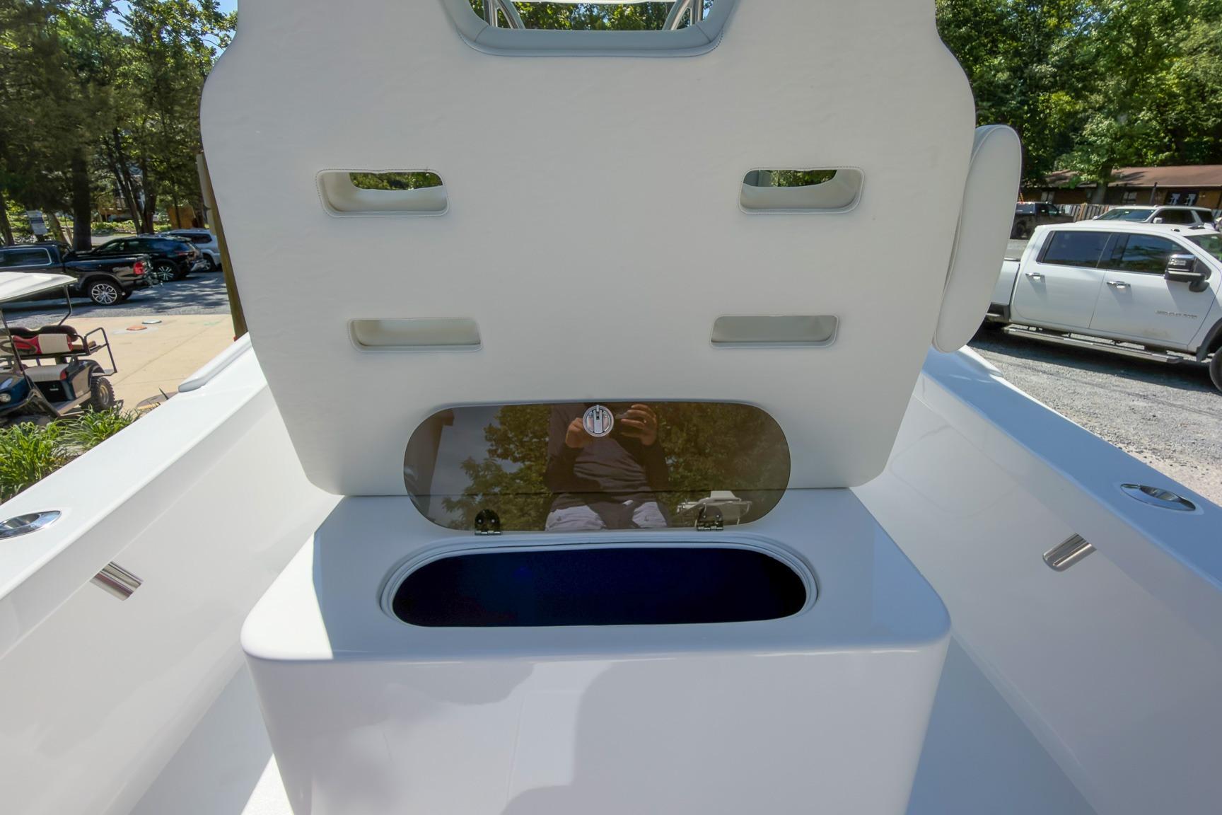 2025 Weaver 25 boat interior with open storage compartment, parked vehicles in background.