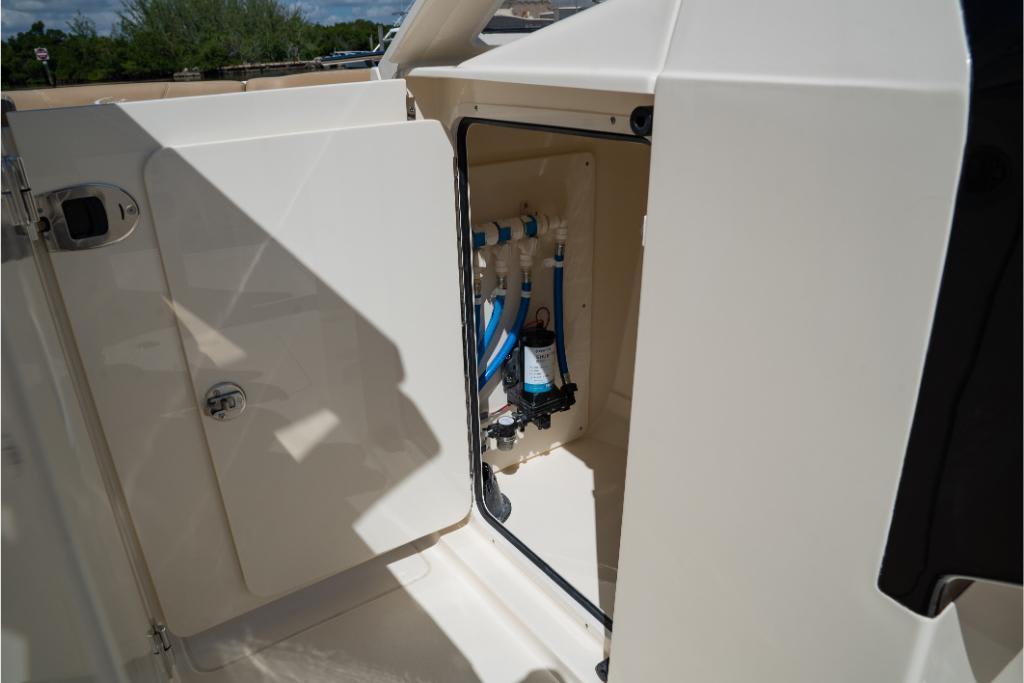 Open storage compartment on 2023 Scout 240 Dorado boat, showing internal plumbing.