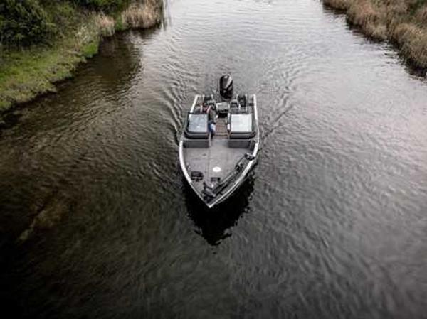 2026 Lund 2075 IMPACT XS boat navigating a narrow waterway surrounded by greenery.