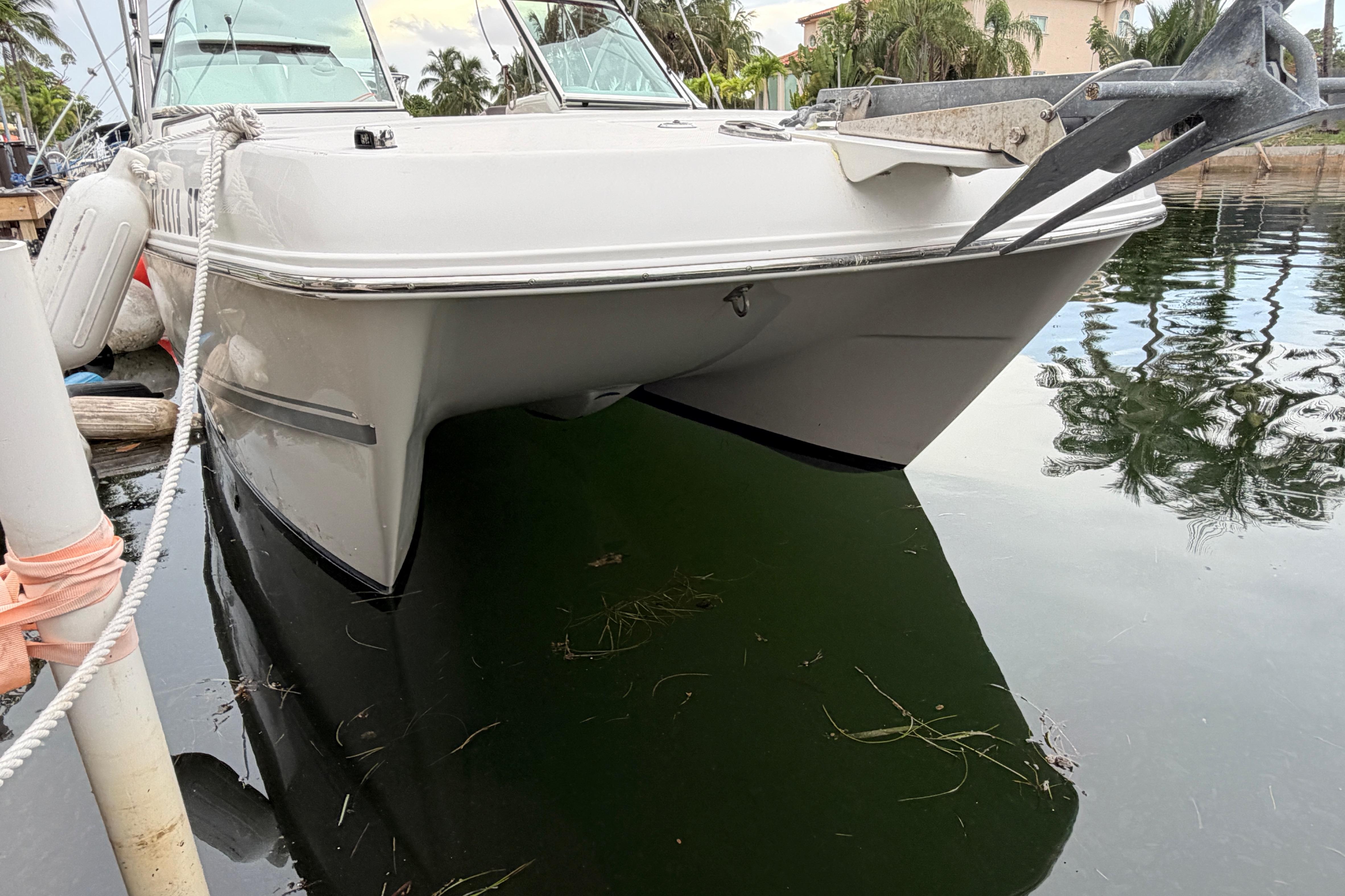 2019 World Cat 230 DC boat docked on calm water, featuring sleek design and anchor.