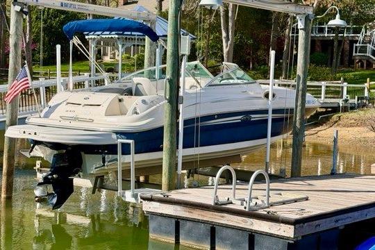 2008 Sea Ray 240 Sundeck boat docked on a lift by a lakeside pier.