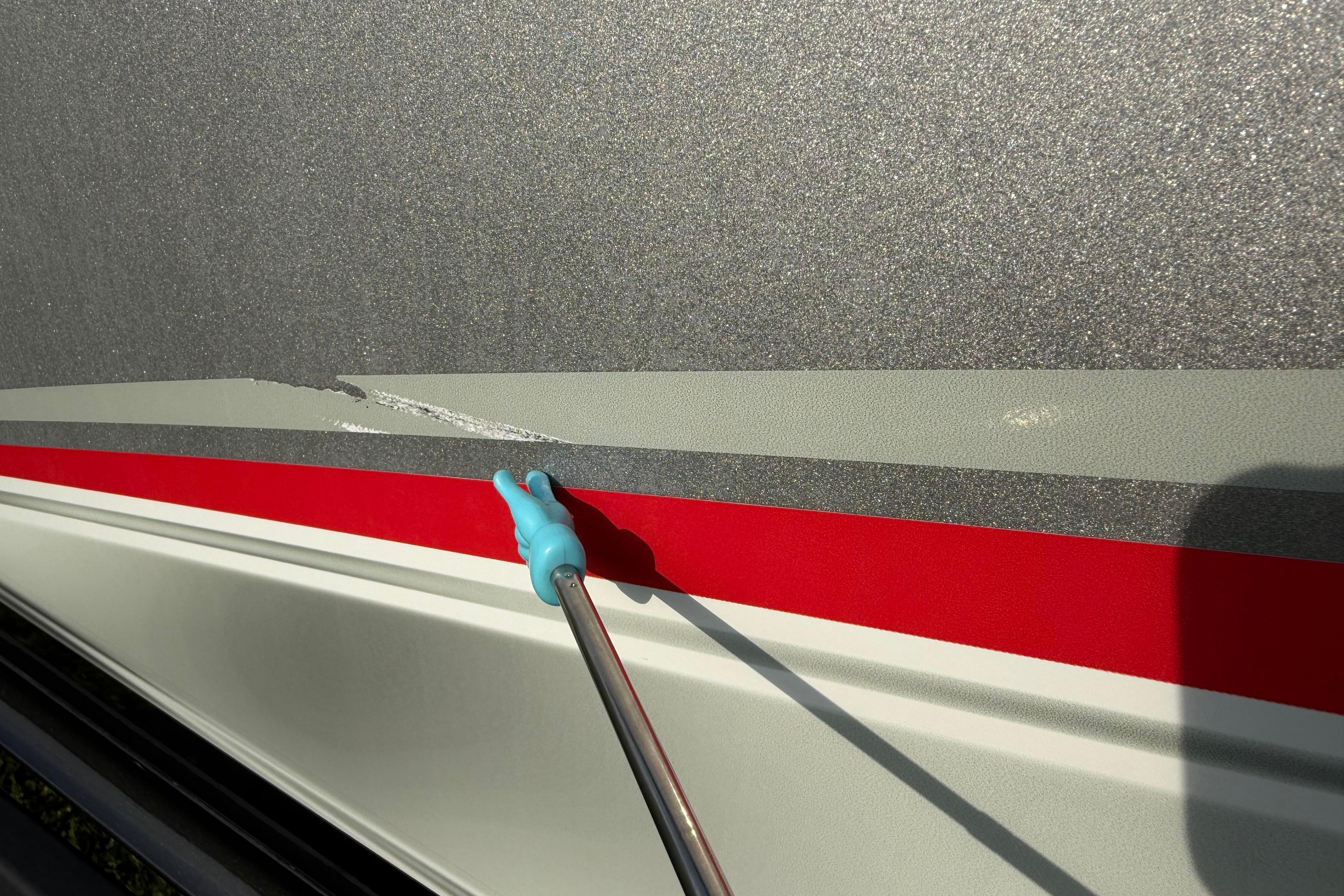 2019 Alumacraft Trophy 205 boat with a scratch on the metallic gray and red exterior.