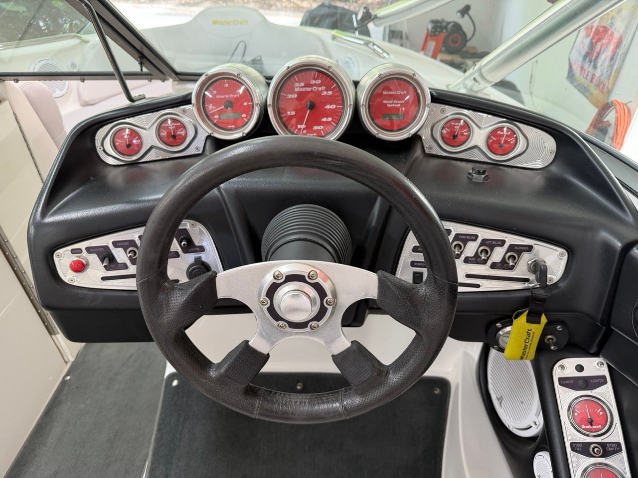 The image shows the dashboard of a 2006 MasterCraft X30 with red gauges and a black steering wheel.