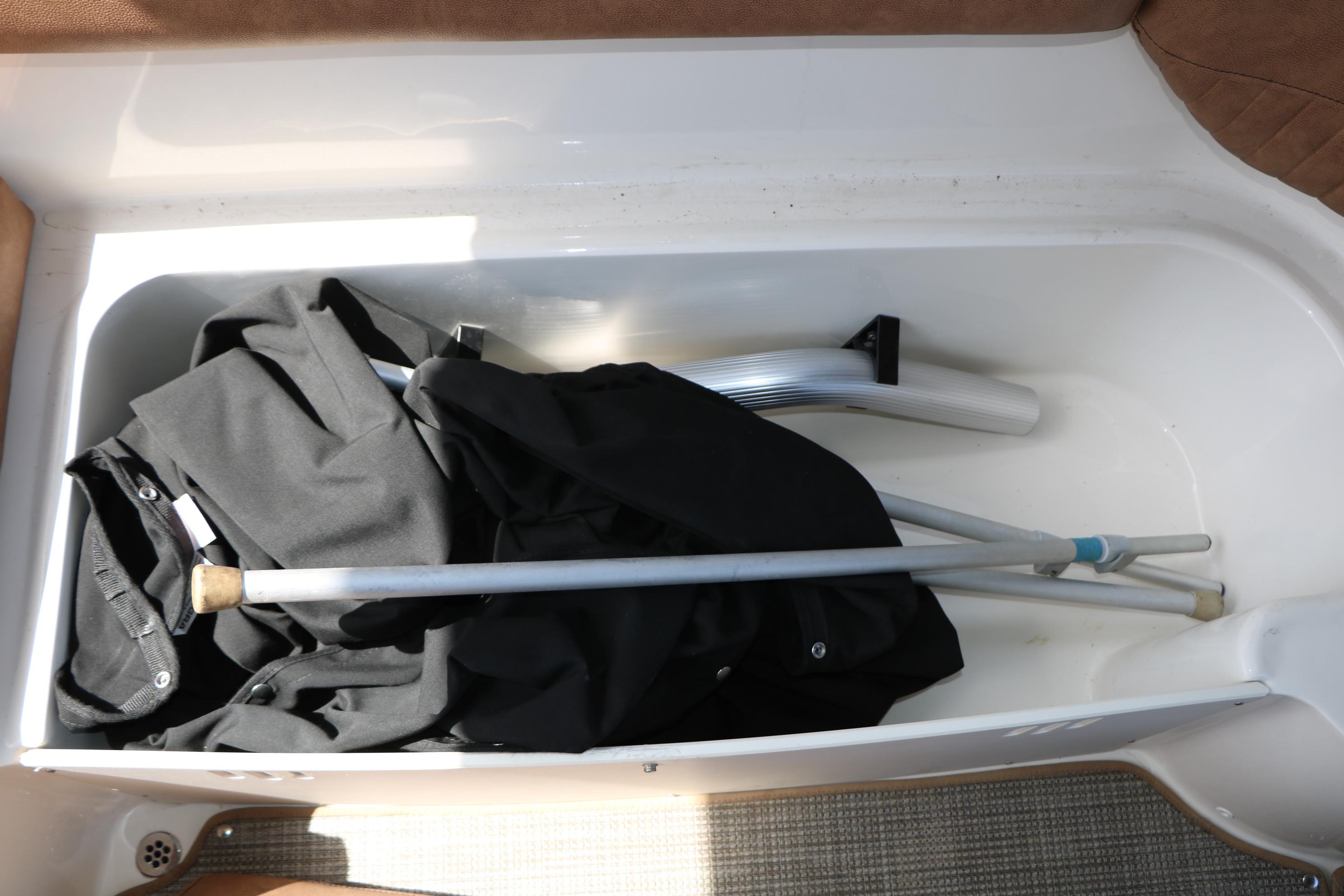 Storage compartment in a 2022 Stingray 192 SC boat with folded fabric and metal poles.