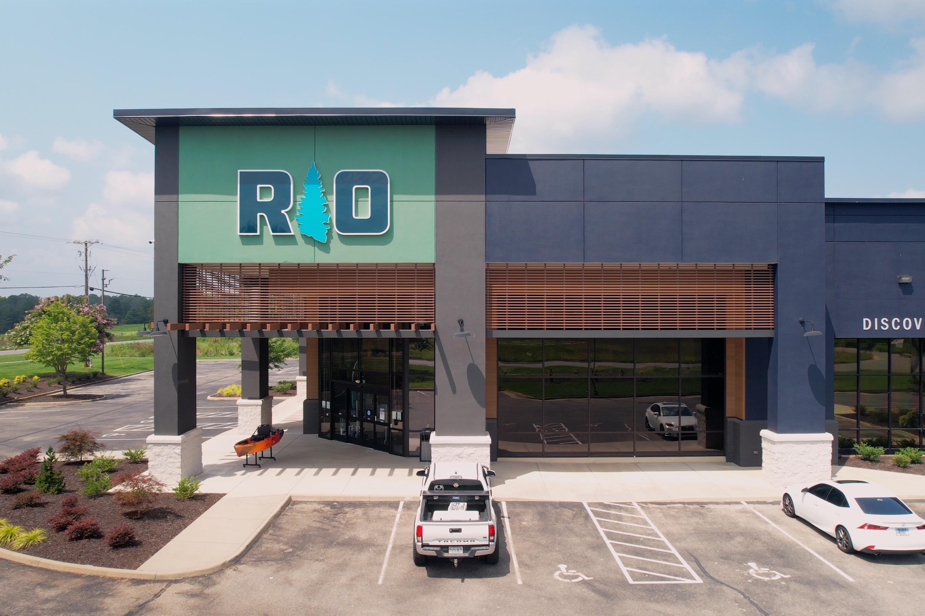 Modern building with "RIO" sign, parking lot, and a white truck in front.