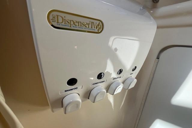 Wall-mounted dispenser with shampoo, conditioner, and soap in a 2003 Sea Ray 260 Sundancer.