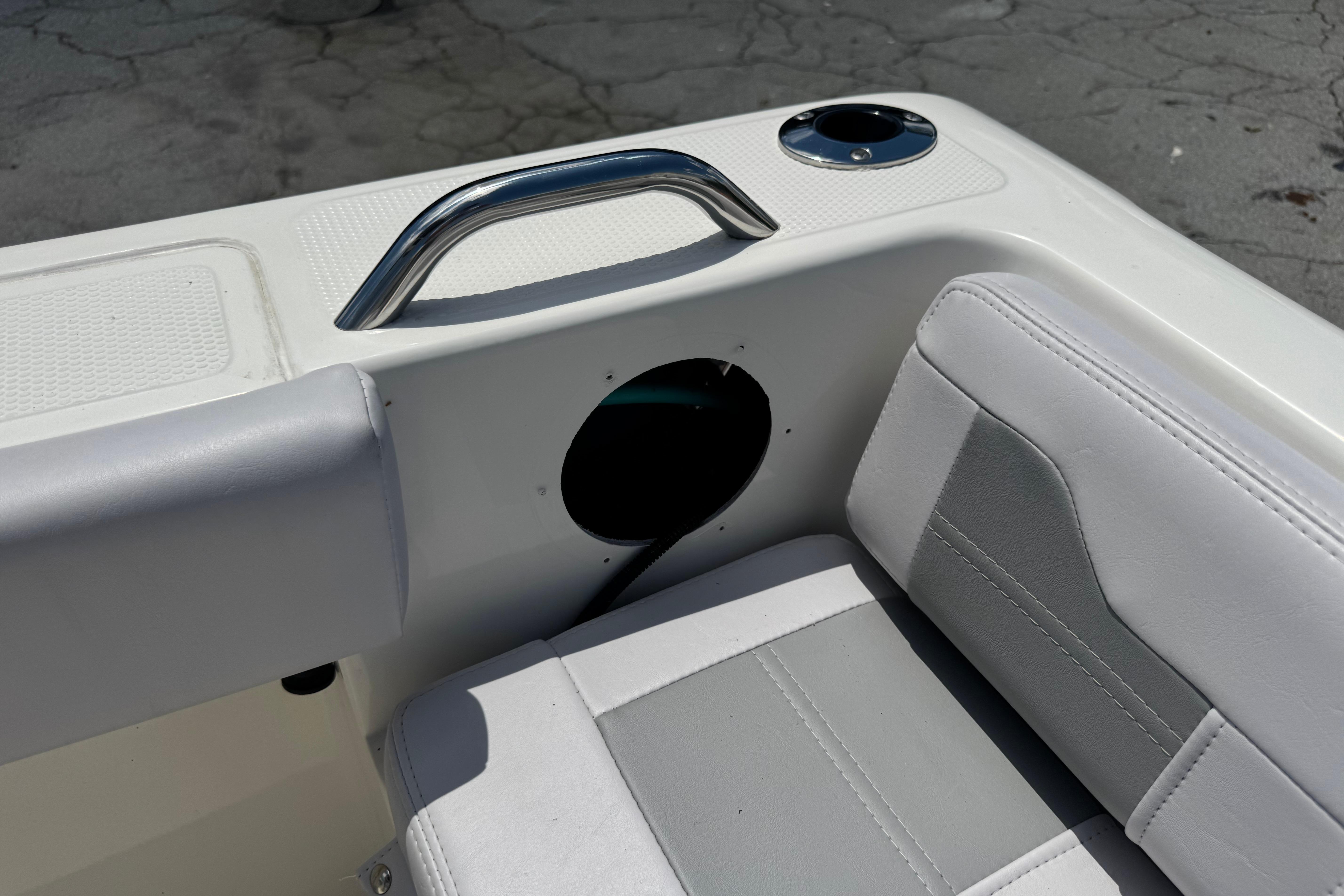 2026 Mako 214 Center Console boat interior with white seating and stainless steel handle.