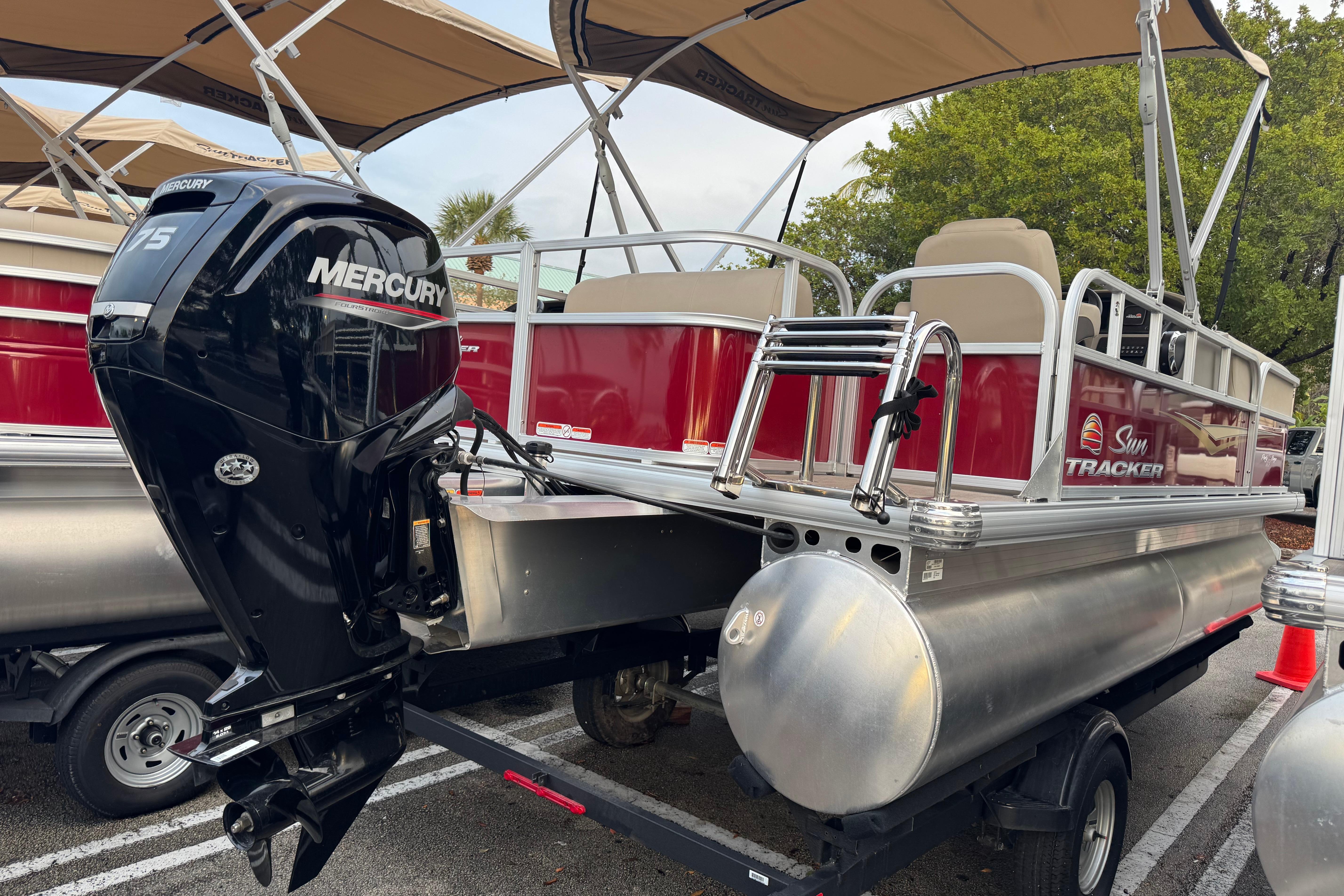 2025 Sun Tracker Party Barge 18 DLX pontoon boat with Mercury engine, parked on trailer.