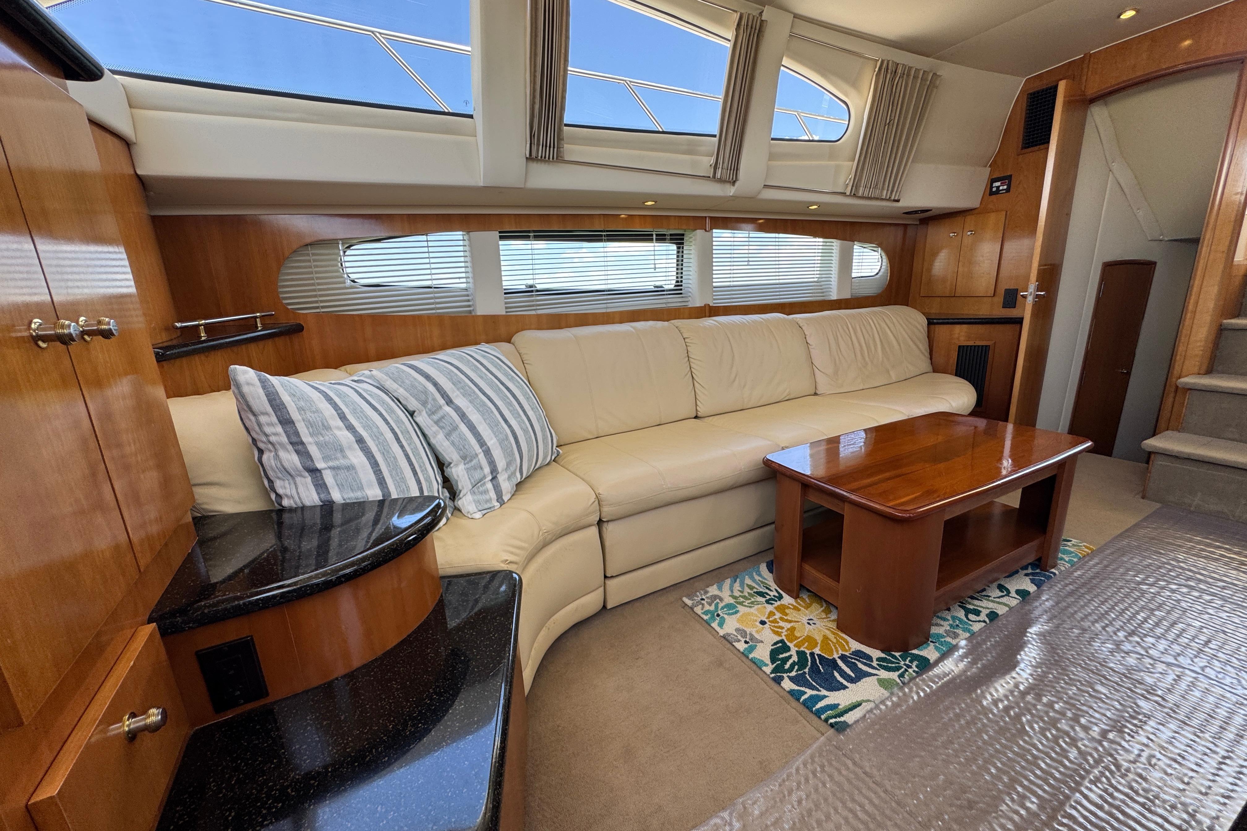 Luxurious interior of 2002 Carver 396 Motor Yacht with beige sofa and wooden accents.