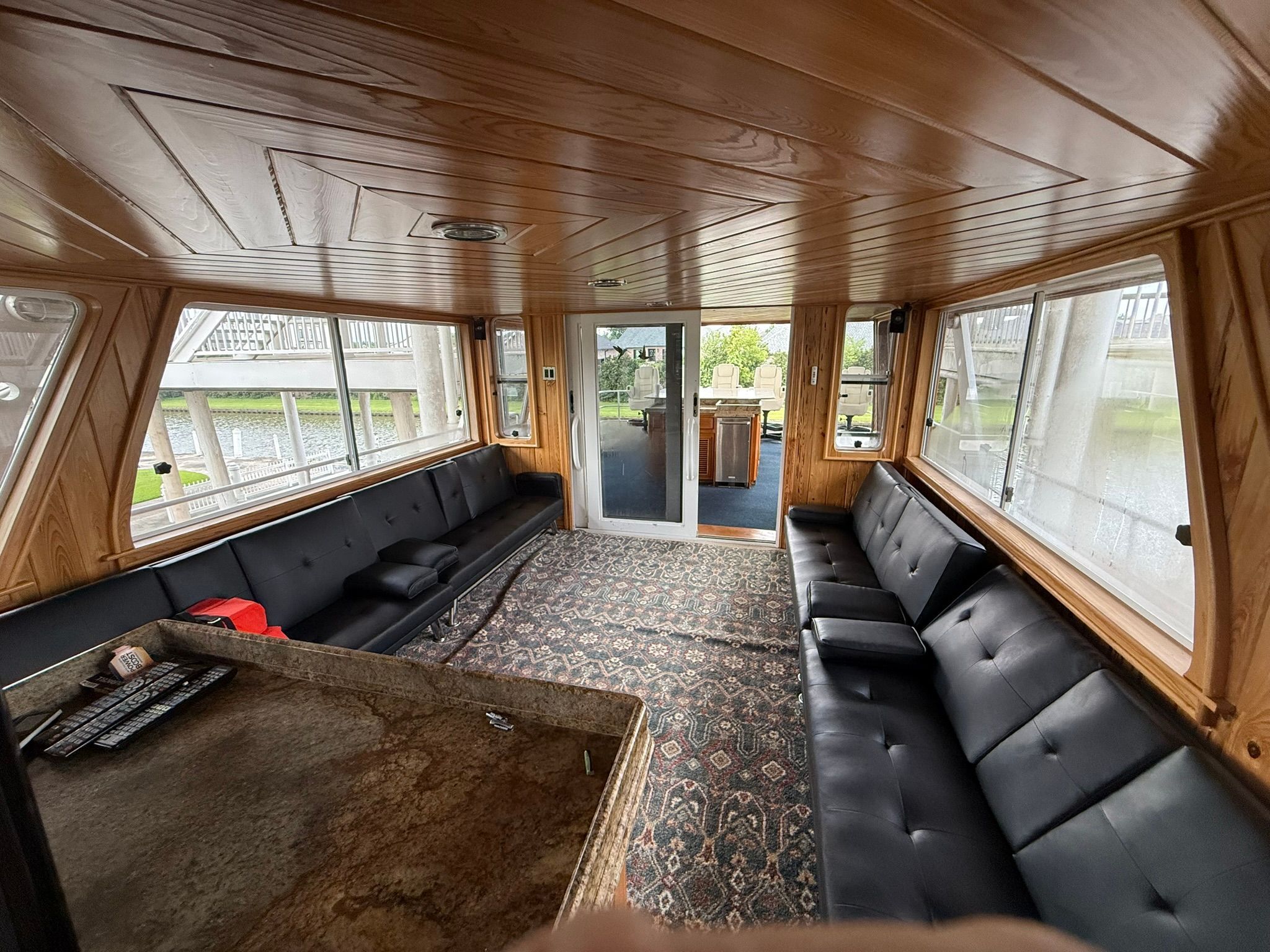 Interior of a houseboat with wooden walls and black sofas.