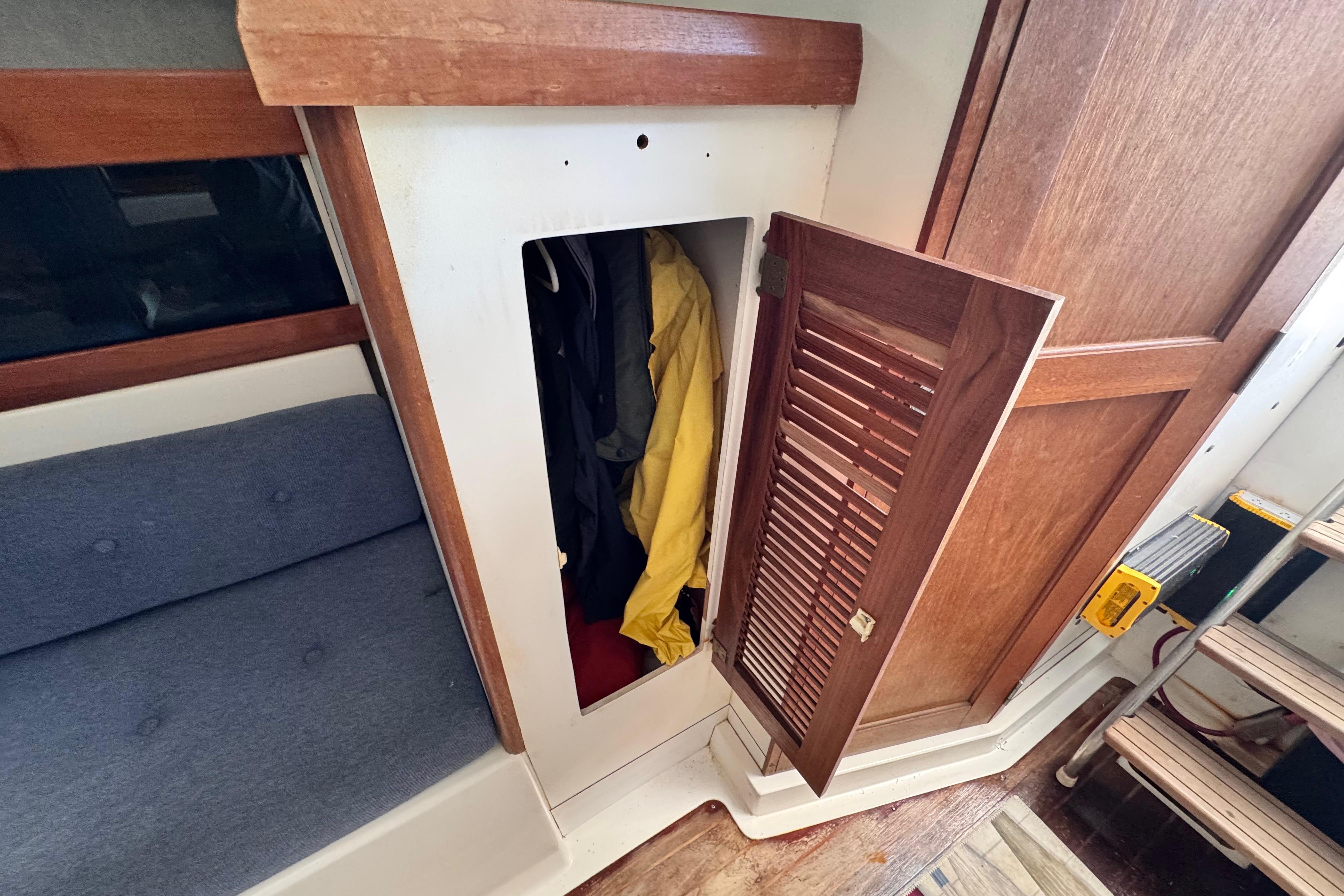 1987 Luhrs Alura 30 interior with open wooden closet and visible clothing.