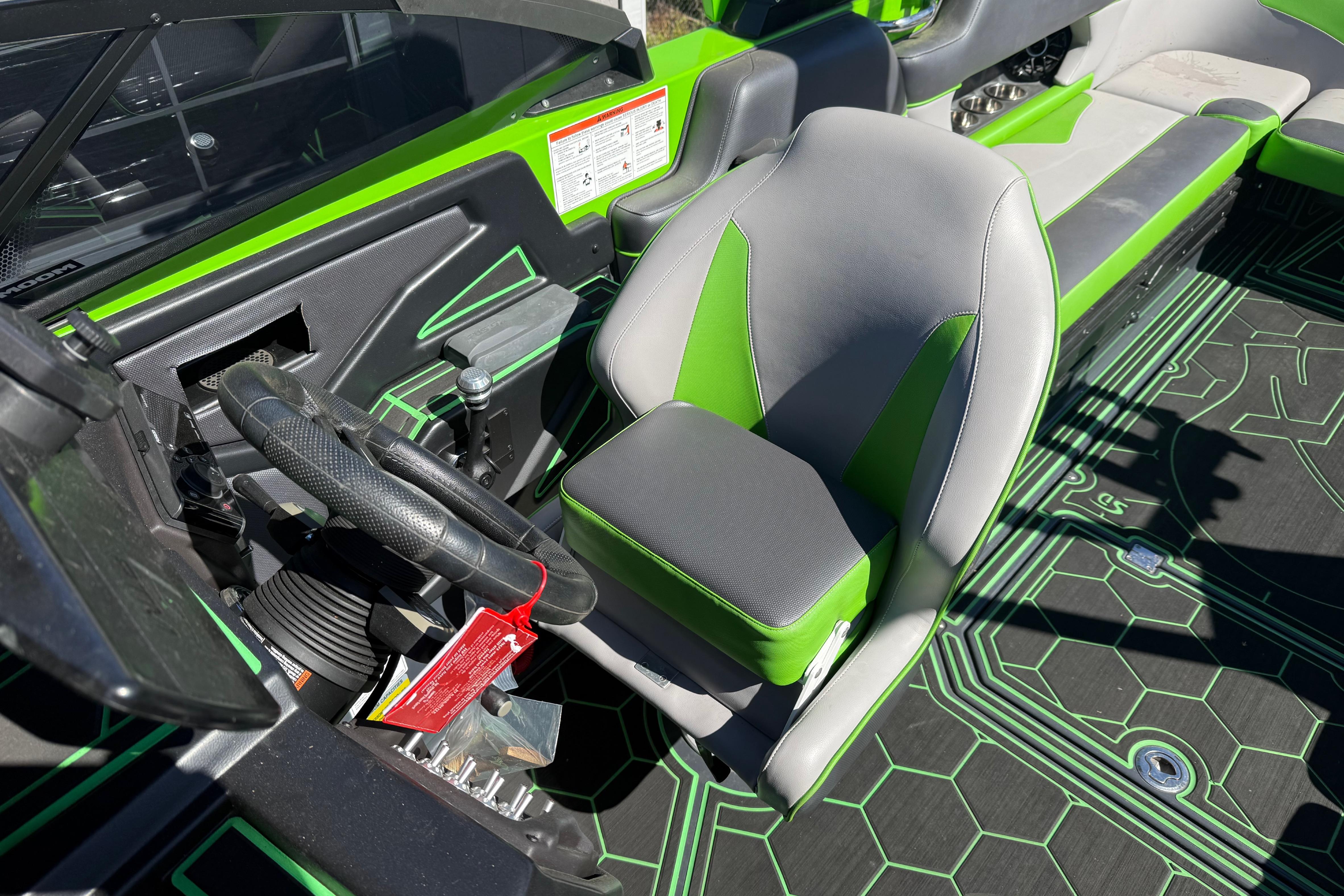2022 Moomba Makai boat interior with green and gray seating and steering wheel.