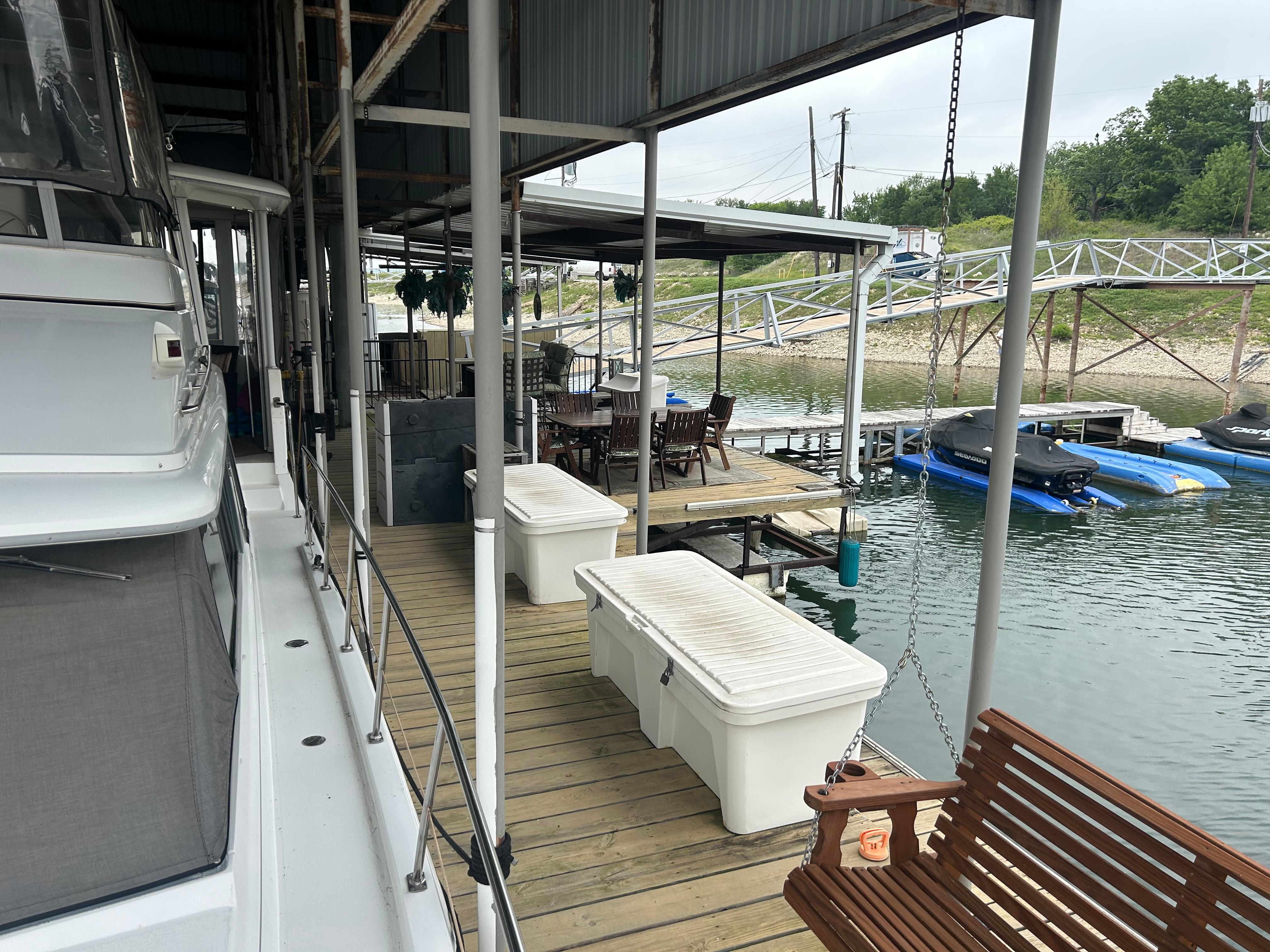1996 Carver 440 Aft Cabin Motor Yacht docked beside a wooden pier with seating area.