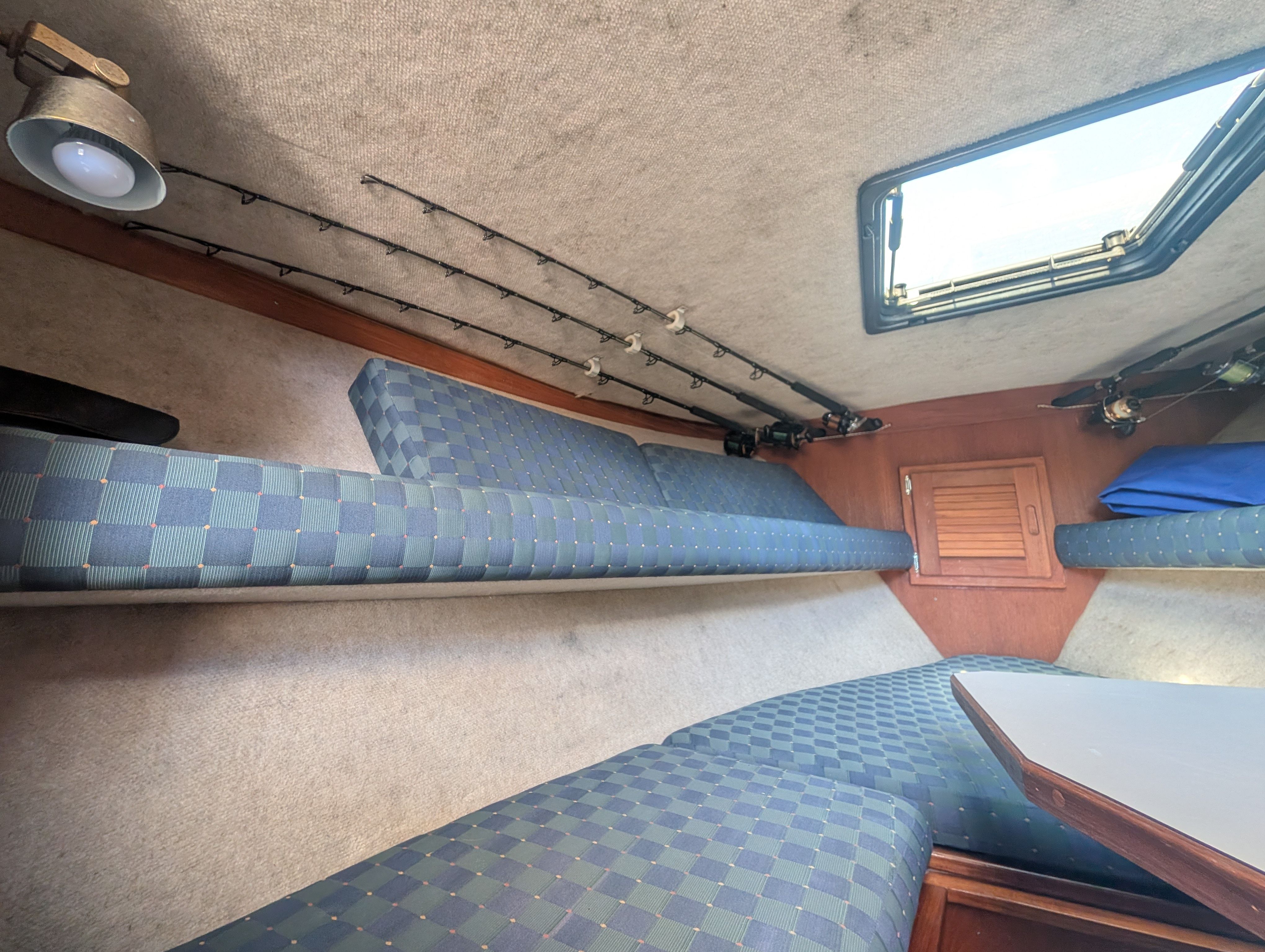 Interior of a boat with cushioned seating and fishing rods.