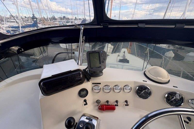 1987 Tollycraft 34 Sundeck Motor Yacht helm with navigation instruments and marina view.