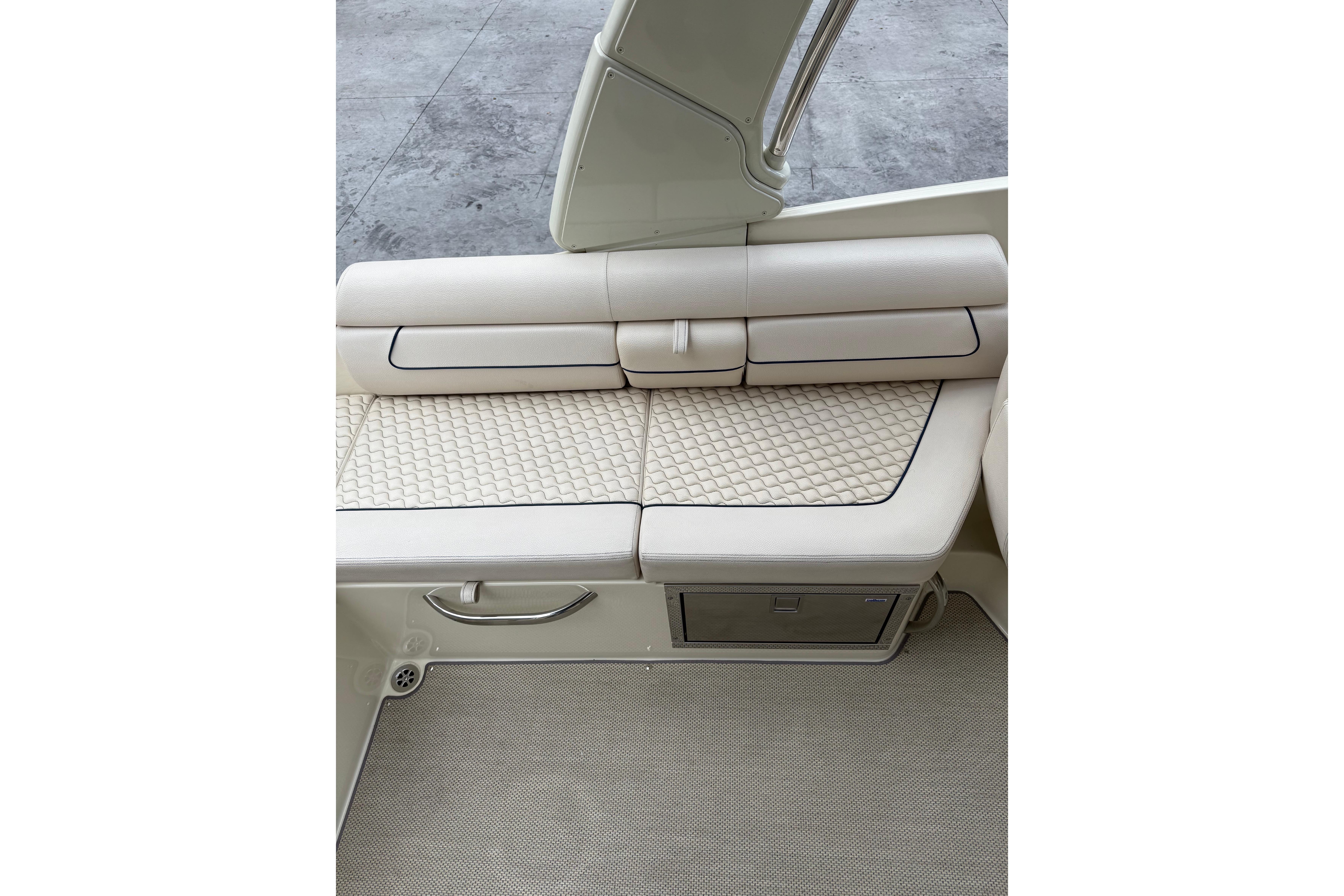 2019 Chris-Craft Launch 28 GT boat interior with beige quilted seating and storage compartment.
