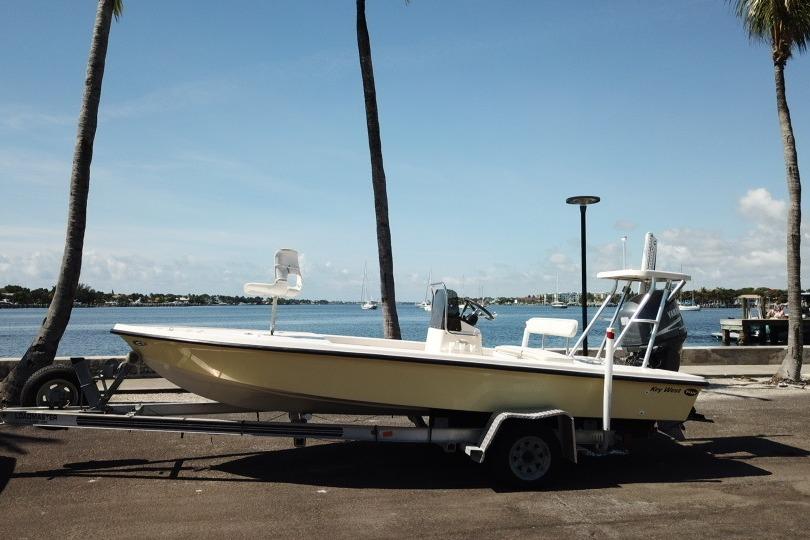 2002 Key West 1760 Stealth boat on trailer by waterfront, palm trees in background.