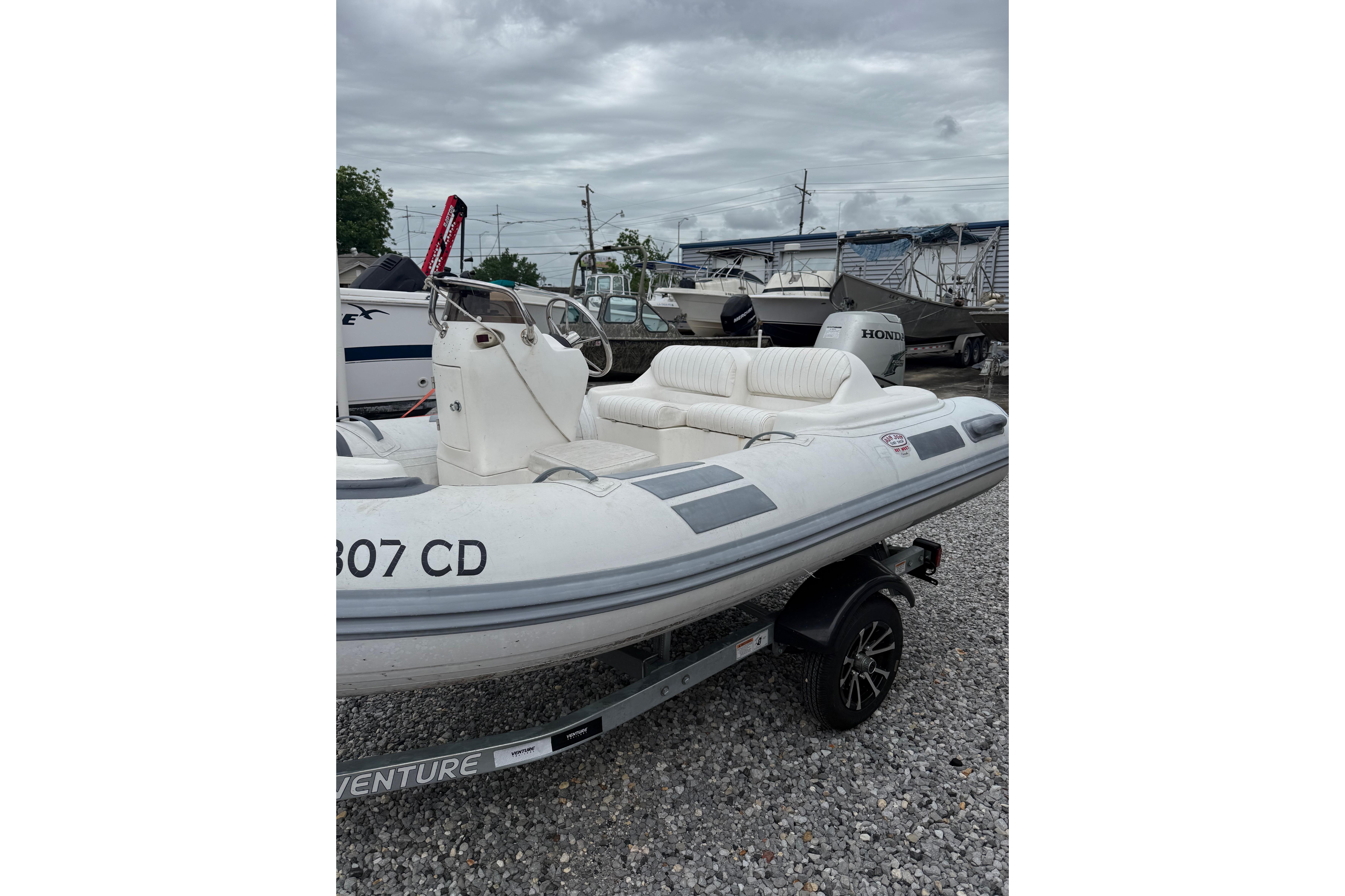 2008 Caribe DL-11 inflatable boat on trailer, parked outdoors under cloudy sky.