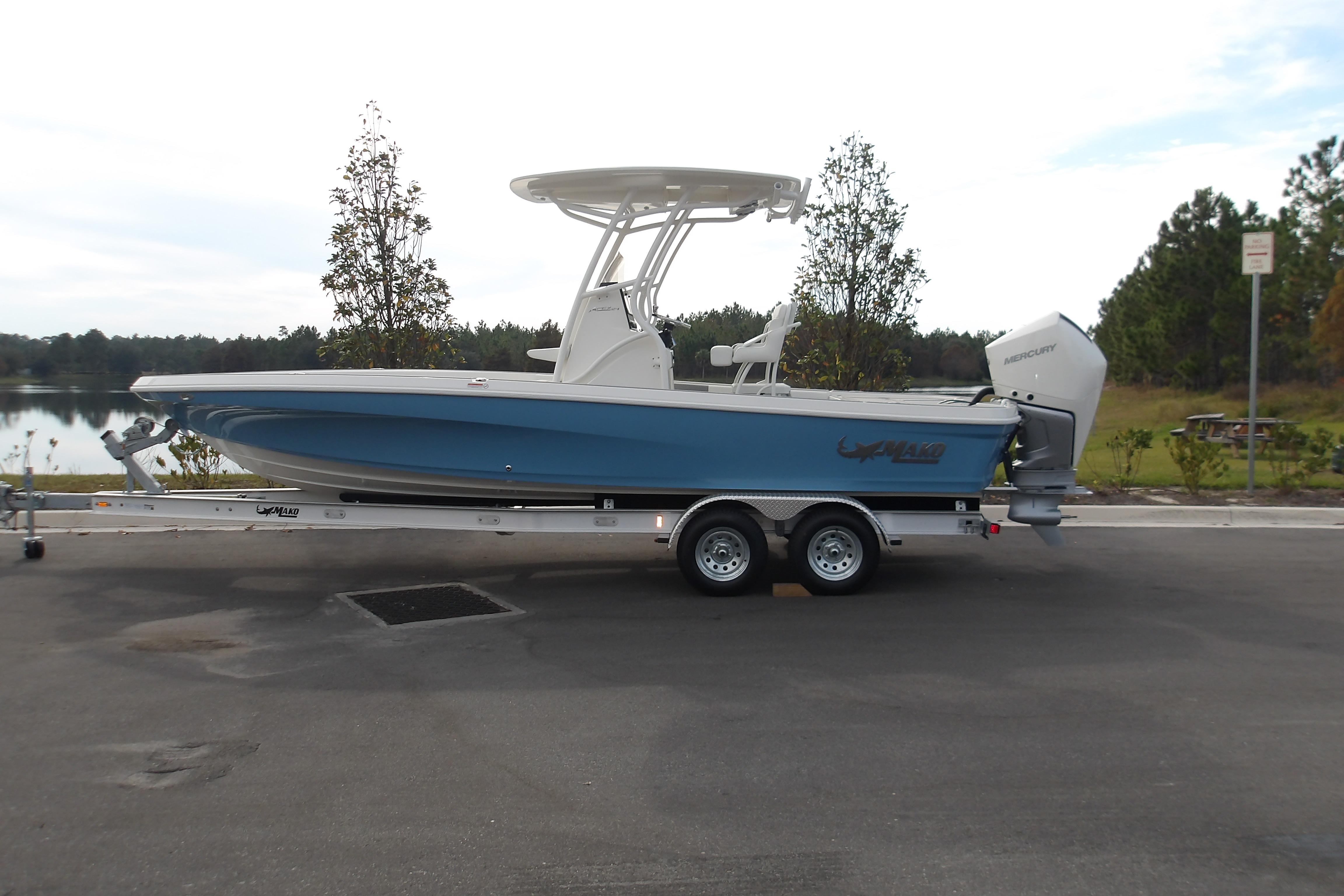2026 Mako 24 APEX boat on trailer, parked near a scenic lake.