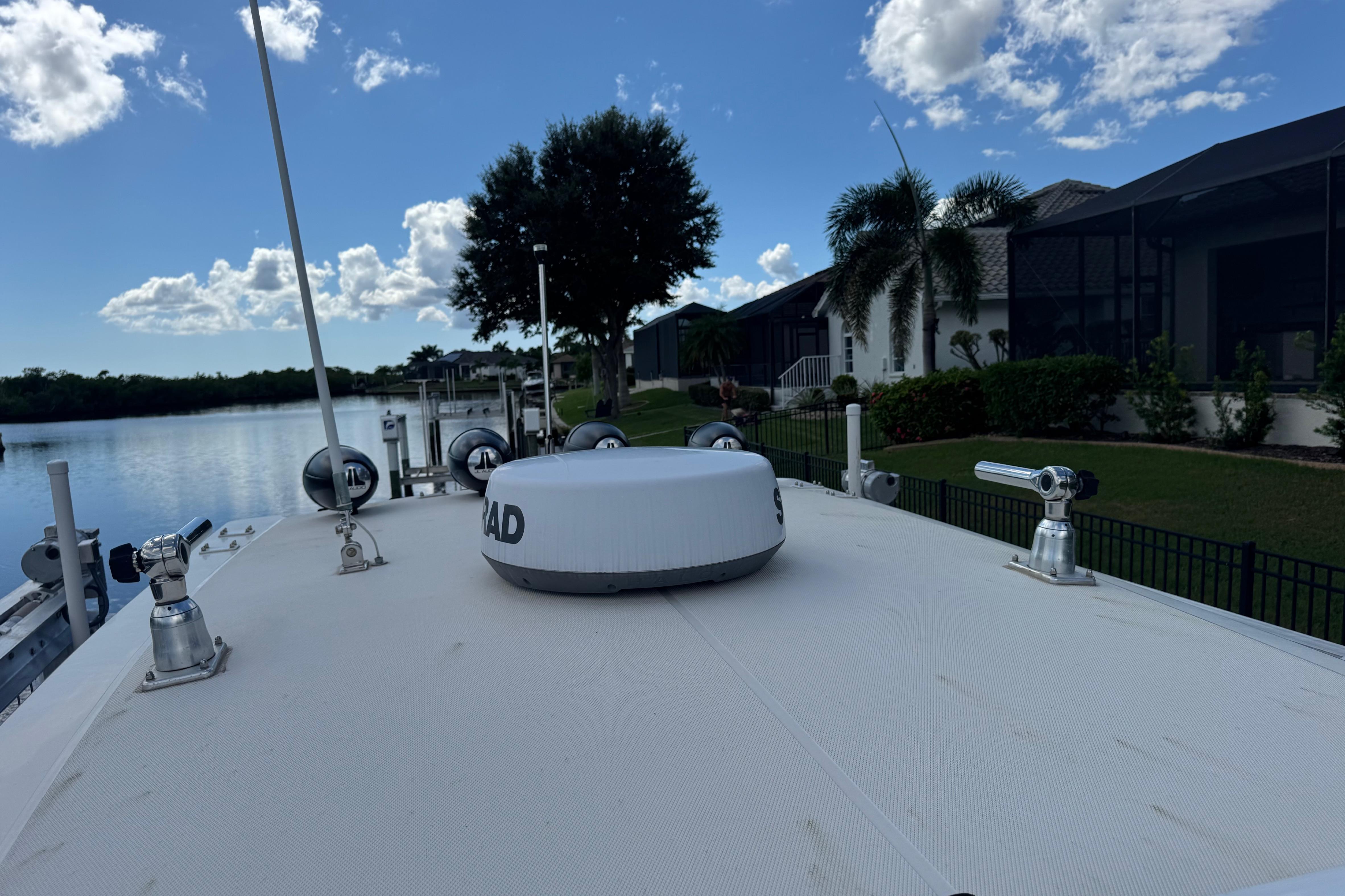 2020 Fountain 38 Center Console boat docked by waterfront homes under a blue sky.