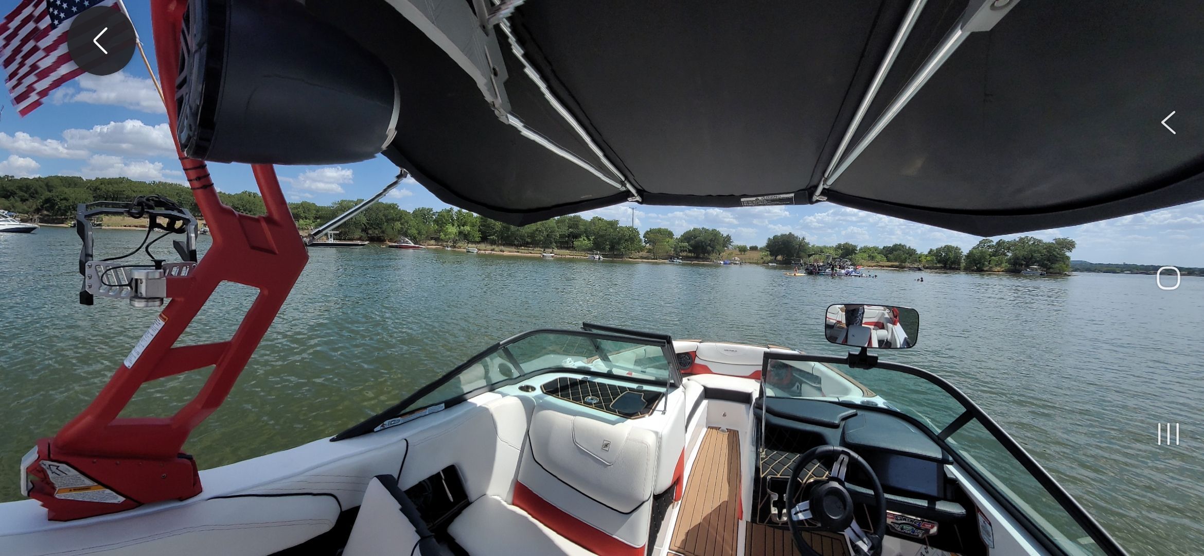 The image shows the cockpit of a 2019 Nautique Super Air Nautique GS22 on a calm lake.