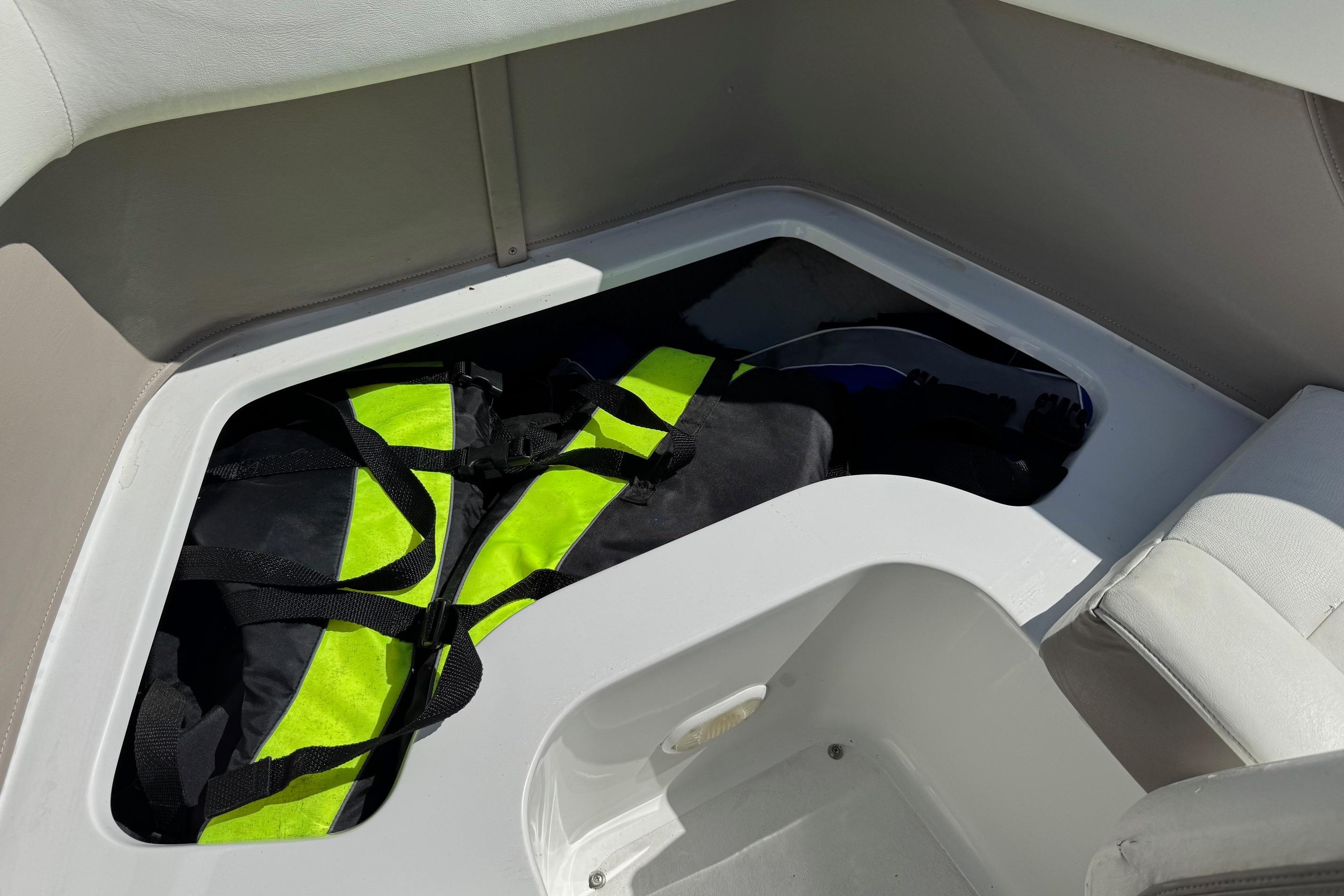 Storage compartment in a 2005 Cobalt 240 boat with life jackets inside.