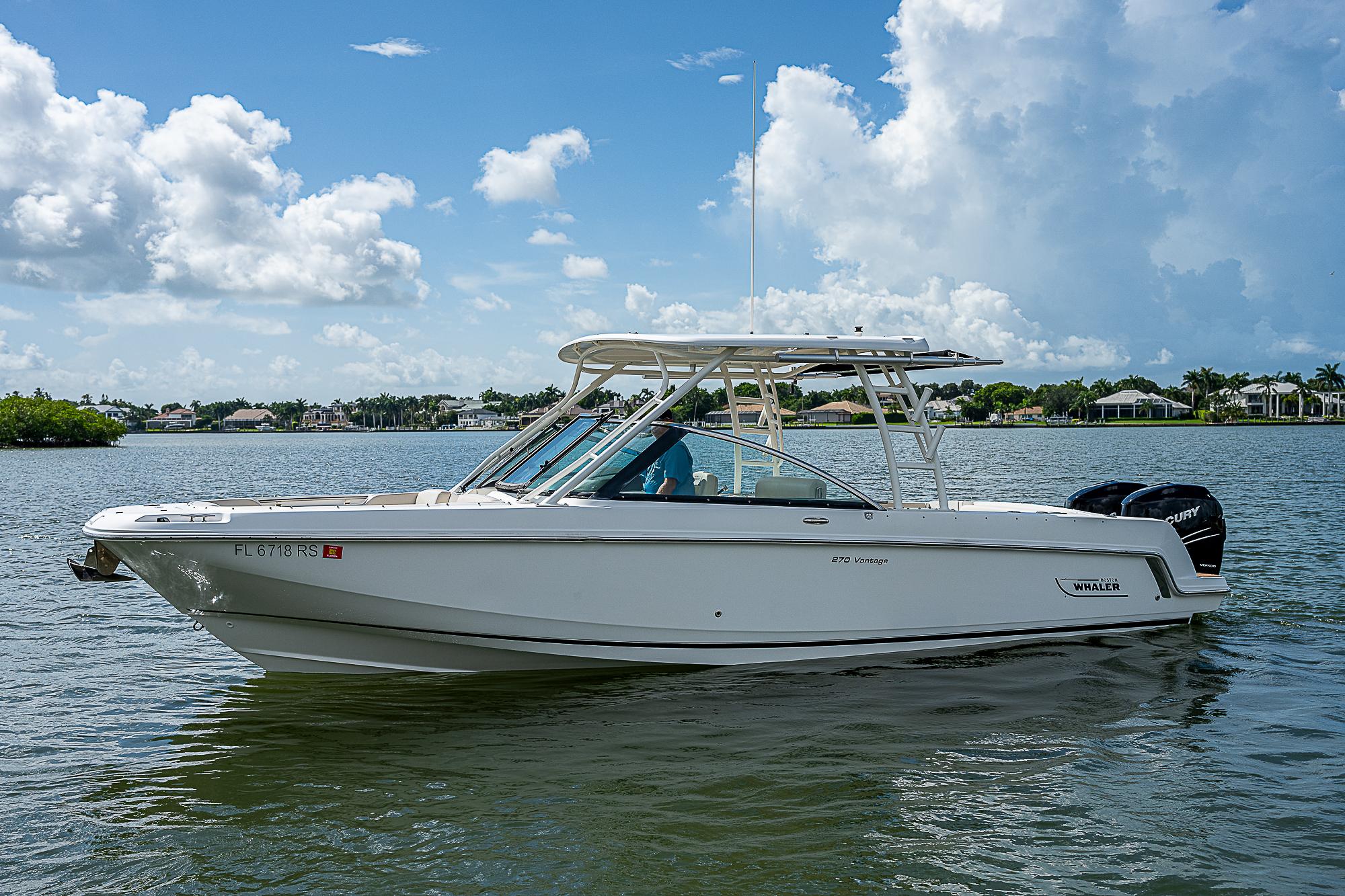 2018 Boston Whaler 270 Vantage boat on a calm lake under a blue sky.