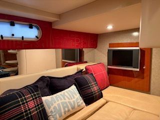 Cozy interior with cushions and a TV in a boat cabin.