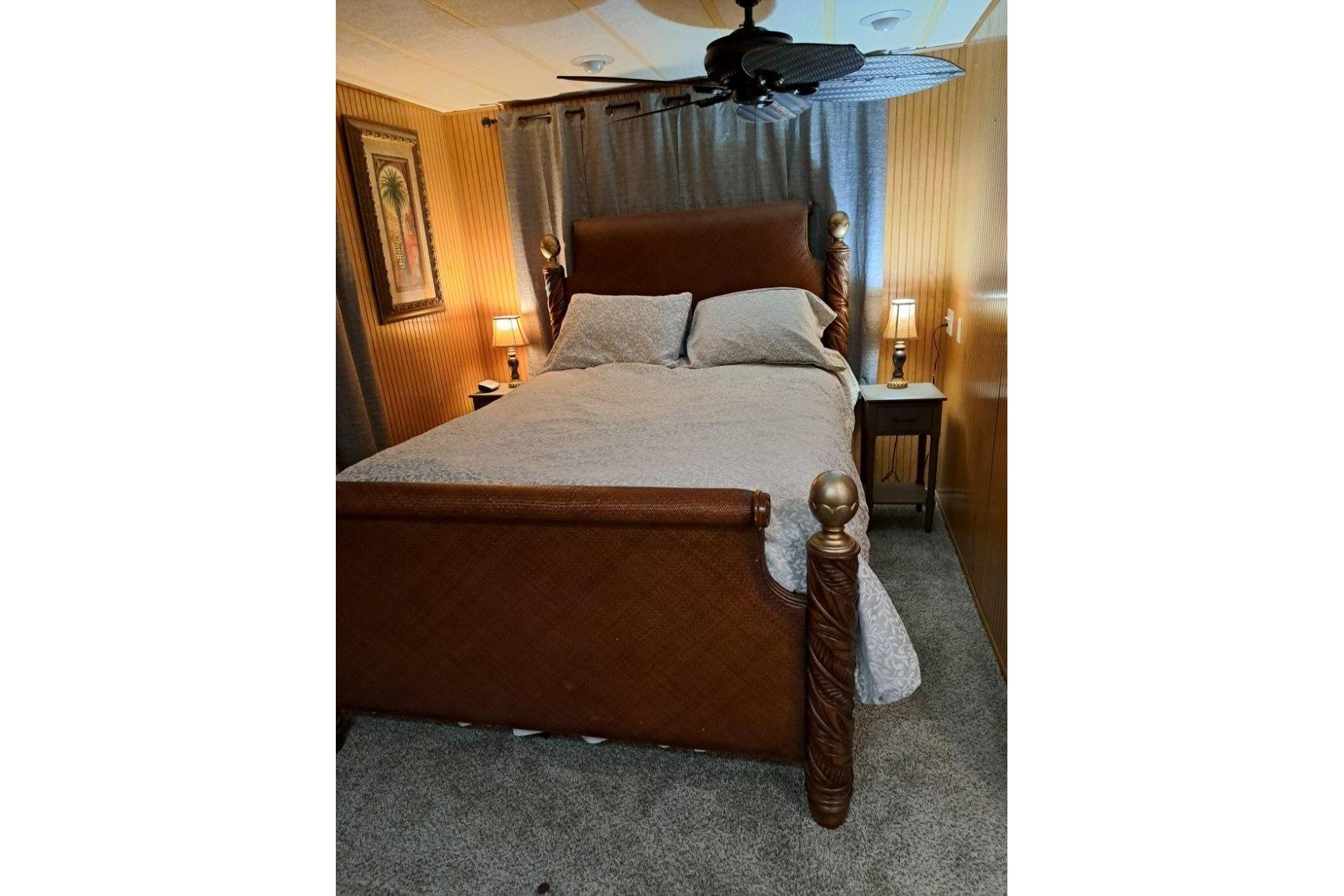 Cozy bedroom with wooden bed frame, elegant lamps, and wall art in a 1990 Sumerset 16 x 70.