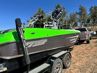 A green 2015 MB F22 Tomcat boat on a trailer outdoors.
