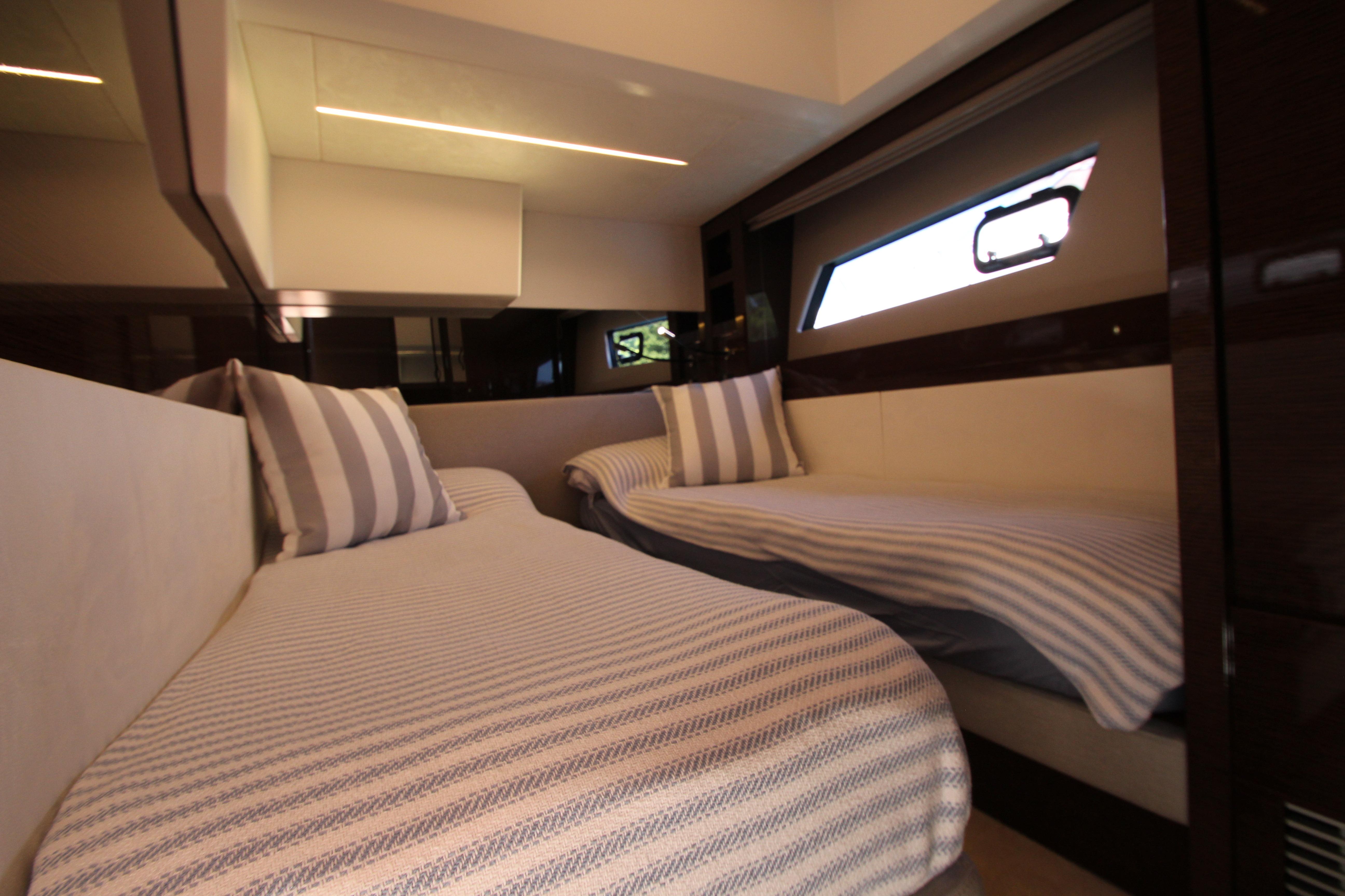 Luxurious twin cabin interior of 2022 Prestige 520 yacht with striped bedding.