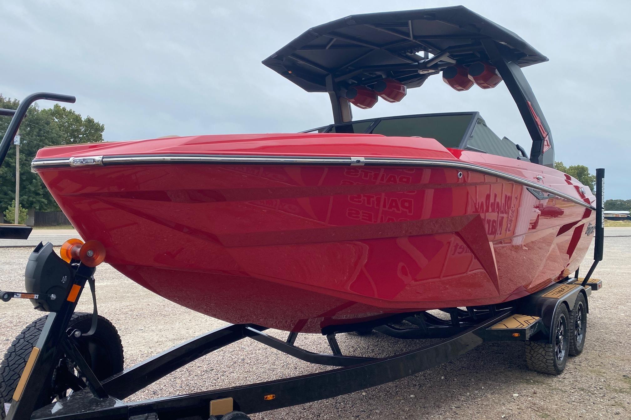 2026 Tigé Z3 boat in vibrant red on a trailer, parked outdoors.