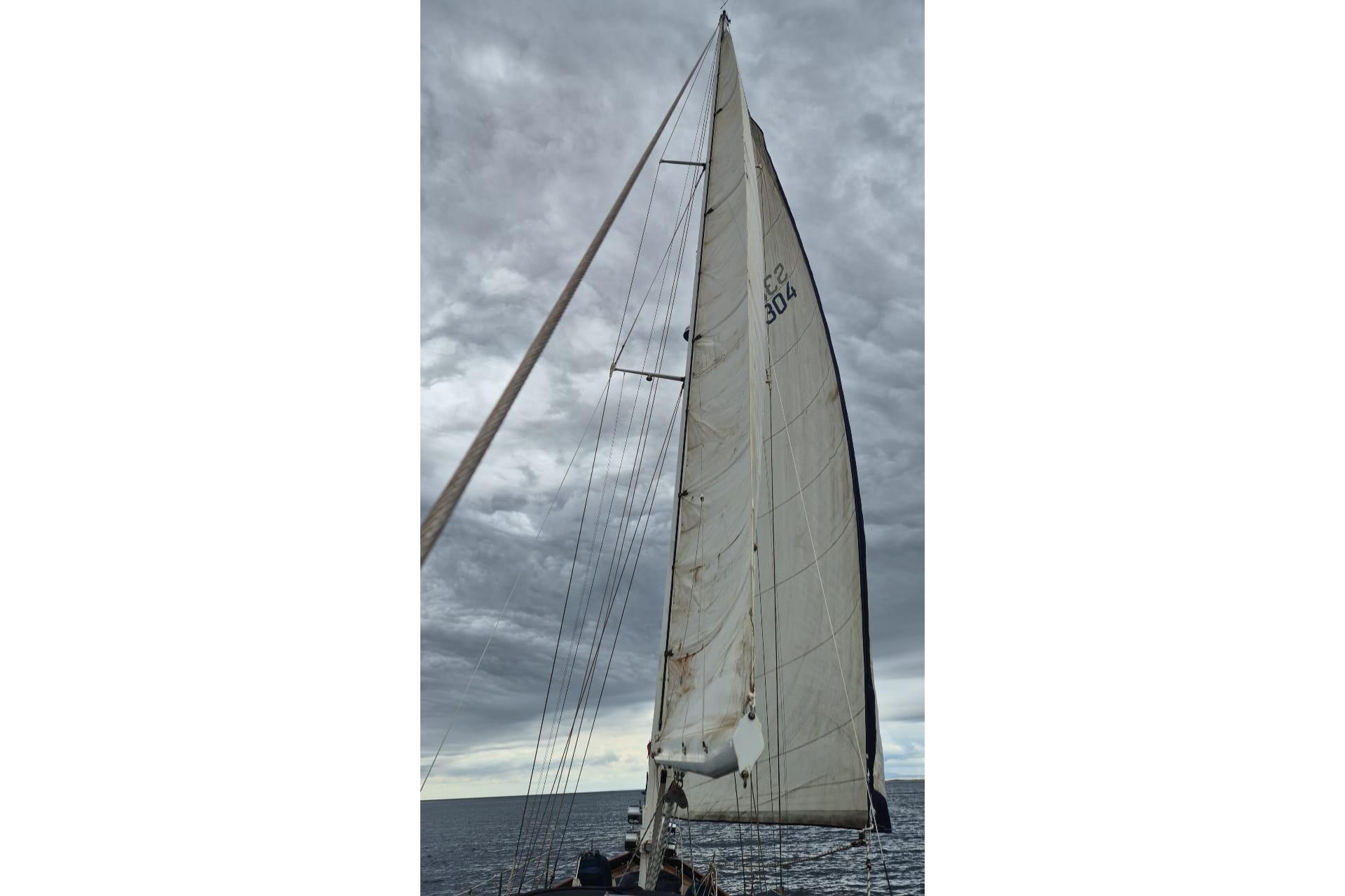 Sailing yacht with tall mast and sails against cloudy sky, Rare Beister Super 1500, 1953.