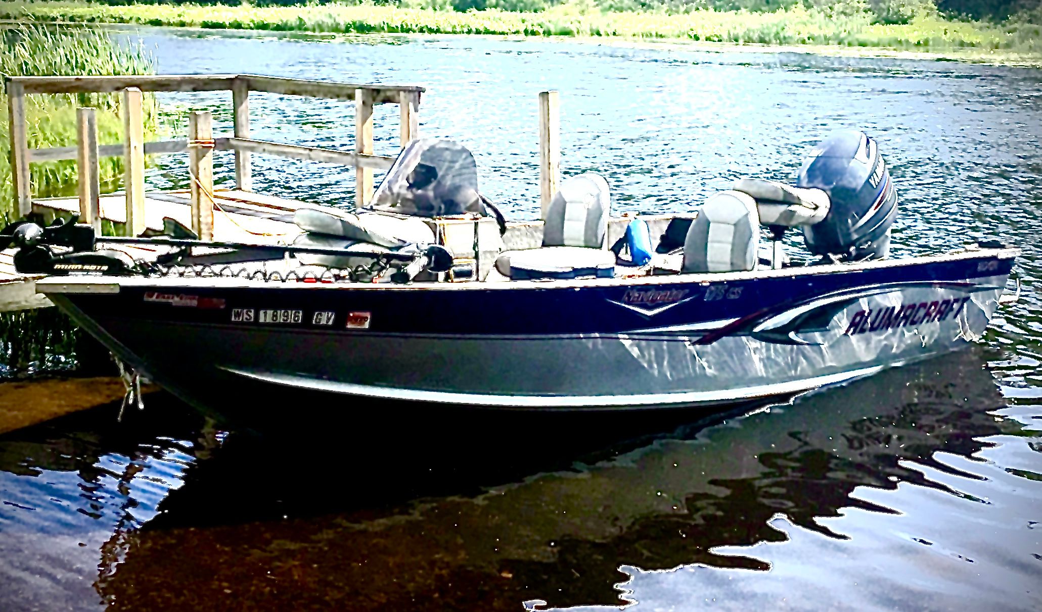 A 2005 Alumacraft Navigator 175CS boat docked at a wooden pier on calm water.