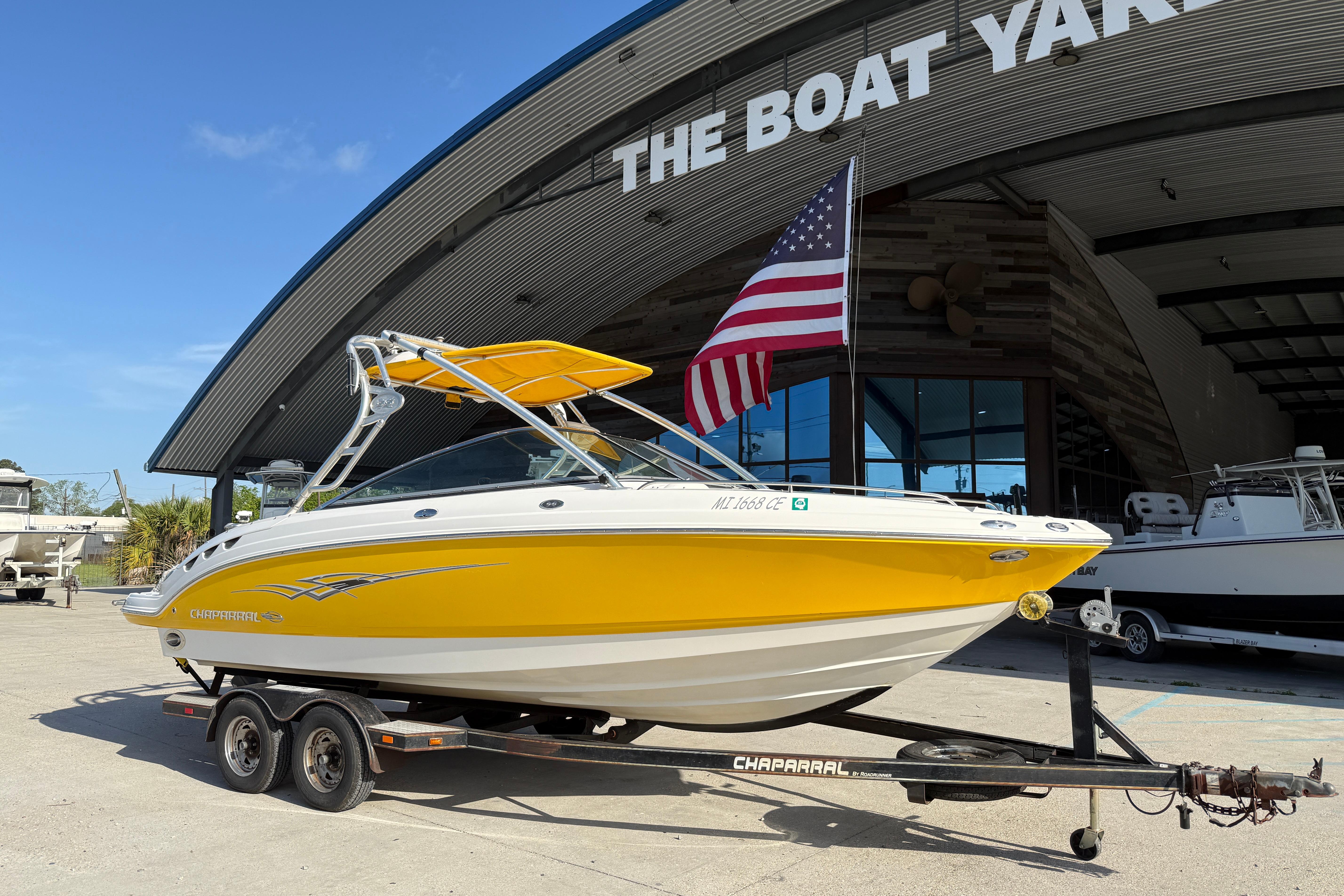 Yellow 2008 Chaparral 236 SSX boat on trailer at The Boat Yard, American flag displayed.