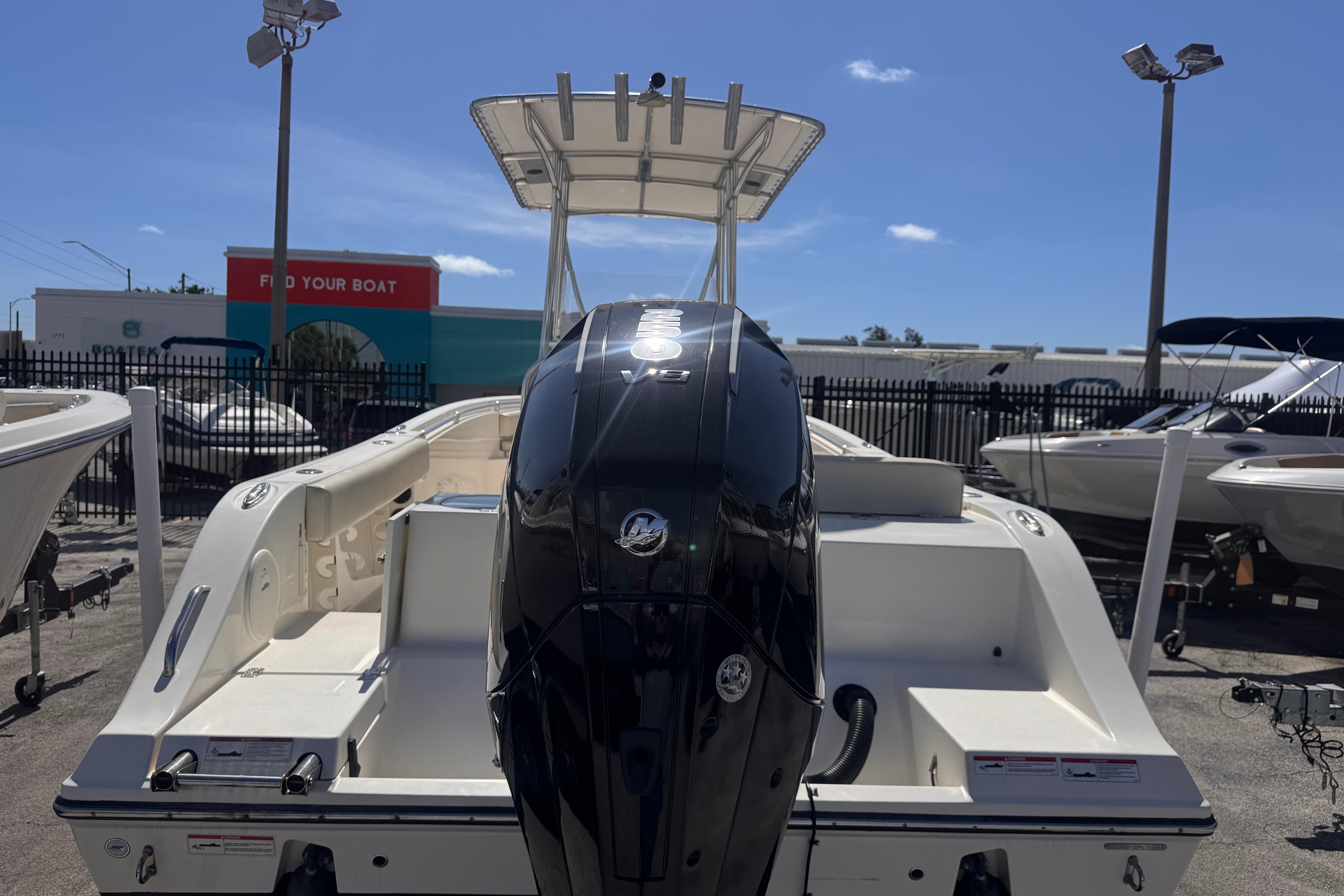 2023 Cobia 237 Center Console boat with powerful outboard motor in a dealership lot.