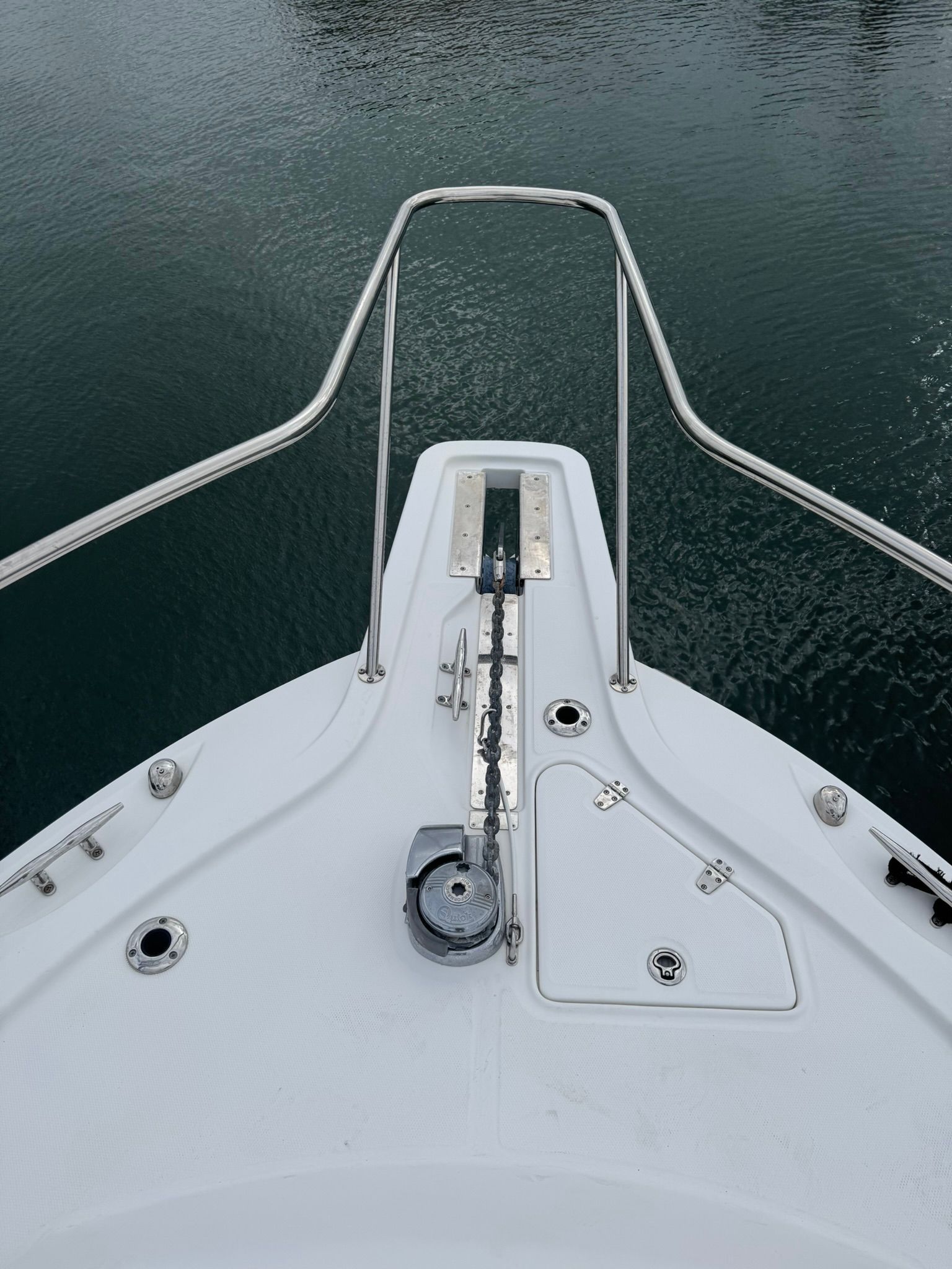 Bow of a boat with anchor windlass and stainless steel railing.