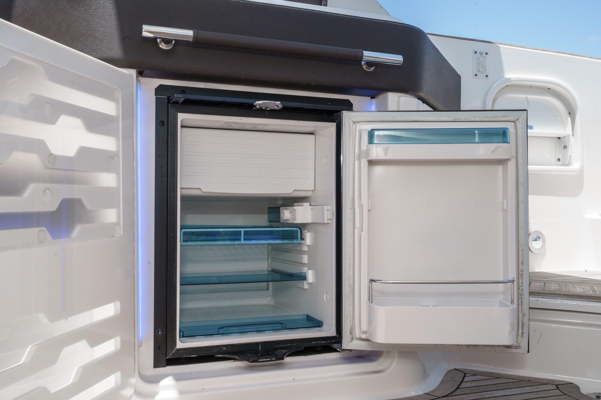 Open refrigerator on 2018 Sea Ray SLX 310 boat, showcasing interior storage space.