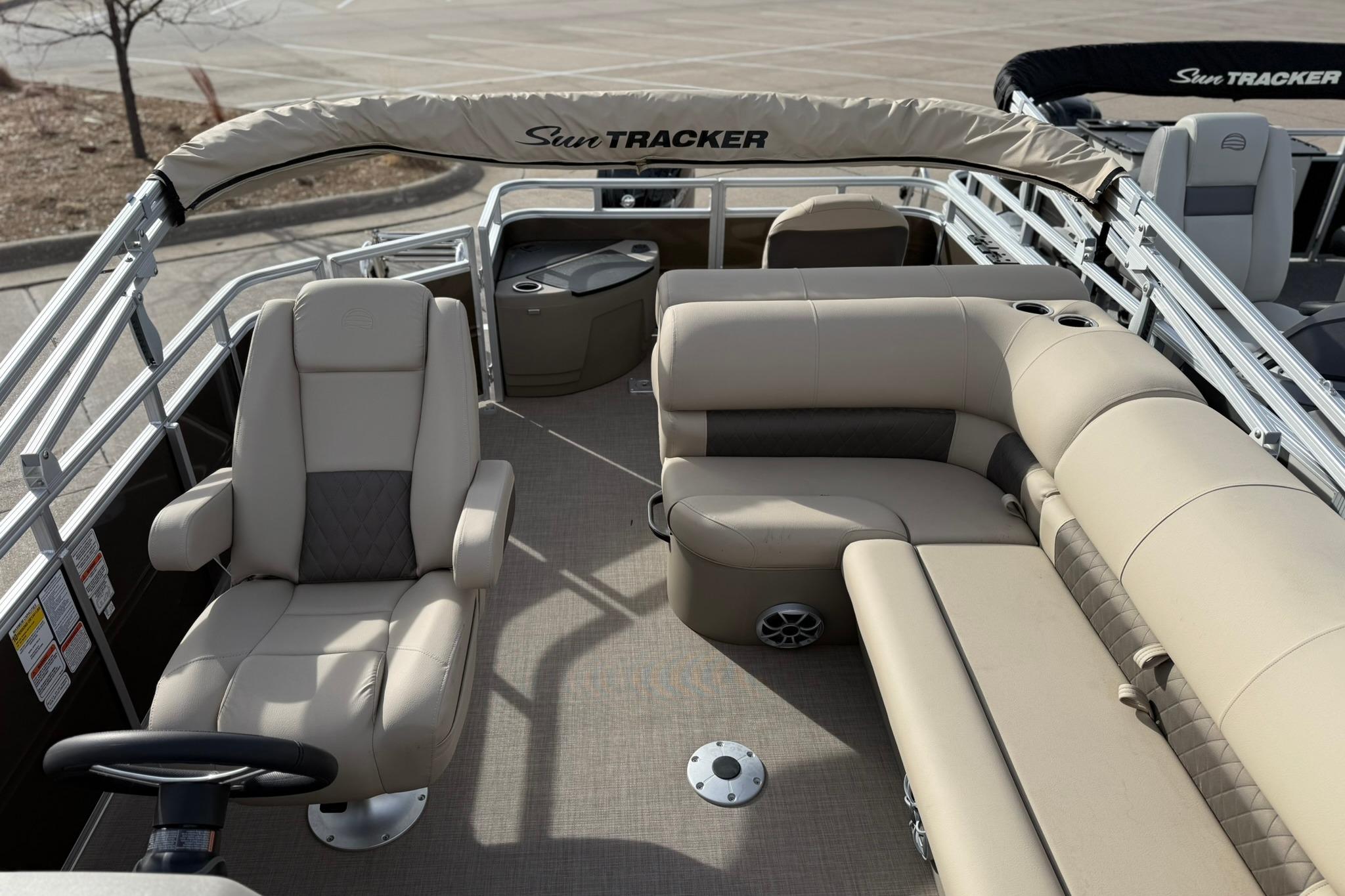 2025 Sun Tracker SportFish 20 DLX pontoon boat interior with beige seating and steering console.
