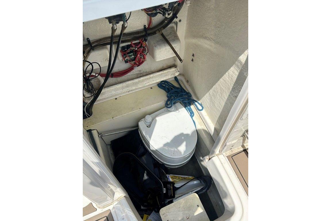 2017 Robalo R200ES boat storage compartment with marine toilet and coiled rope.